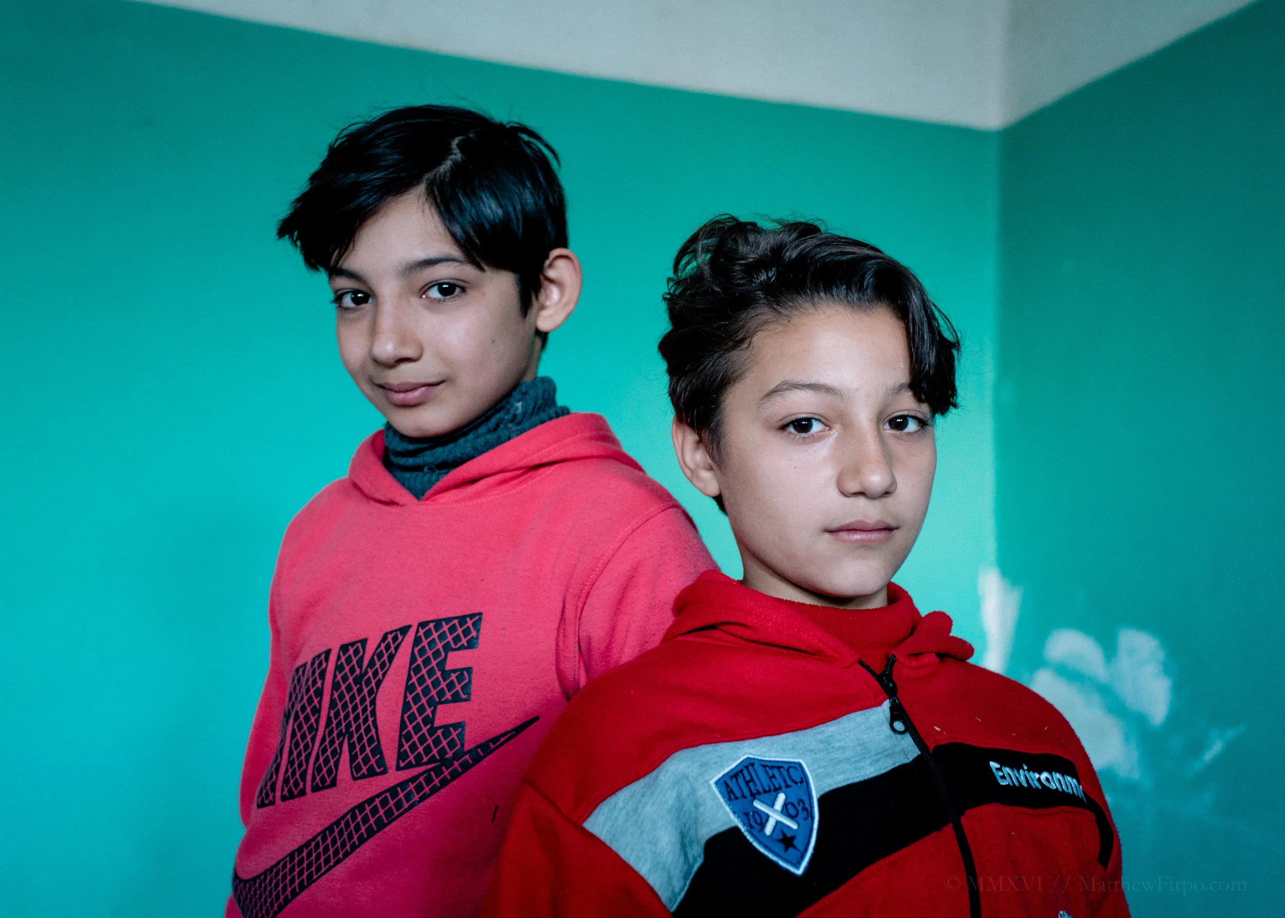 Brothers Leros Refugee Camp, Greece | 37.1305° N, 26.8497° E Muhammad and Abdul-Rahman, 12 and 10 respectively, reminded me of my own brother in so many ways - from their physicality right down to the way they acted, these were just kids caught up in something larger than themselves. As we photographed their father, the boys played in the other room of the abandoned school we'd found as our studio for the day. During our interview, what stuck with me most, even now as I write this caption months later, was Abdul-Rahman's embarrassed admission that one of the things he really missed about home, was his toys. That even as his elder brother held back tears at the thought of never seeing Syria again, for Abdul-Rahman, the reality hadn't fully set in. And that simple distinction was born of the resiliency of youth.