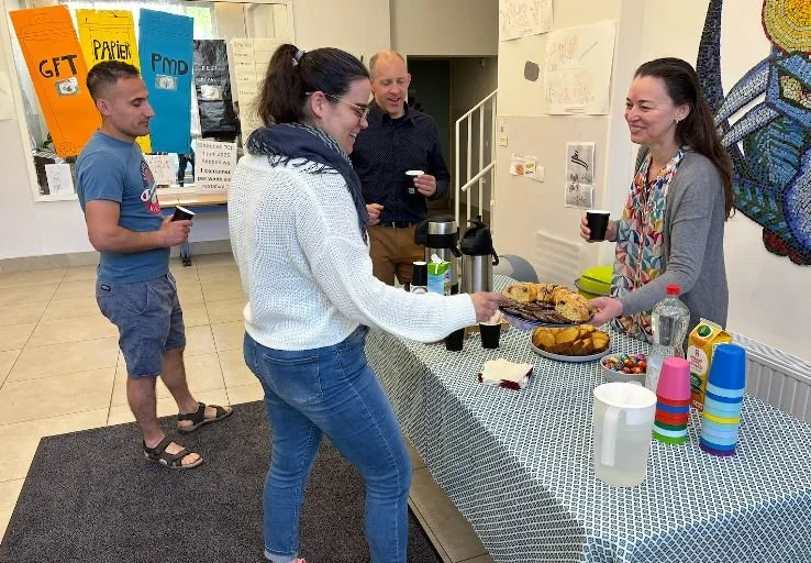 Quatre personnes autour d'une table avec des collations et boissons, en intérieur, avant le début de notre rassemblement