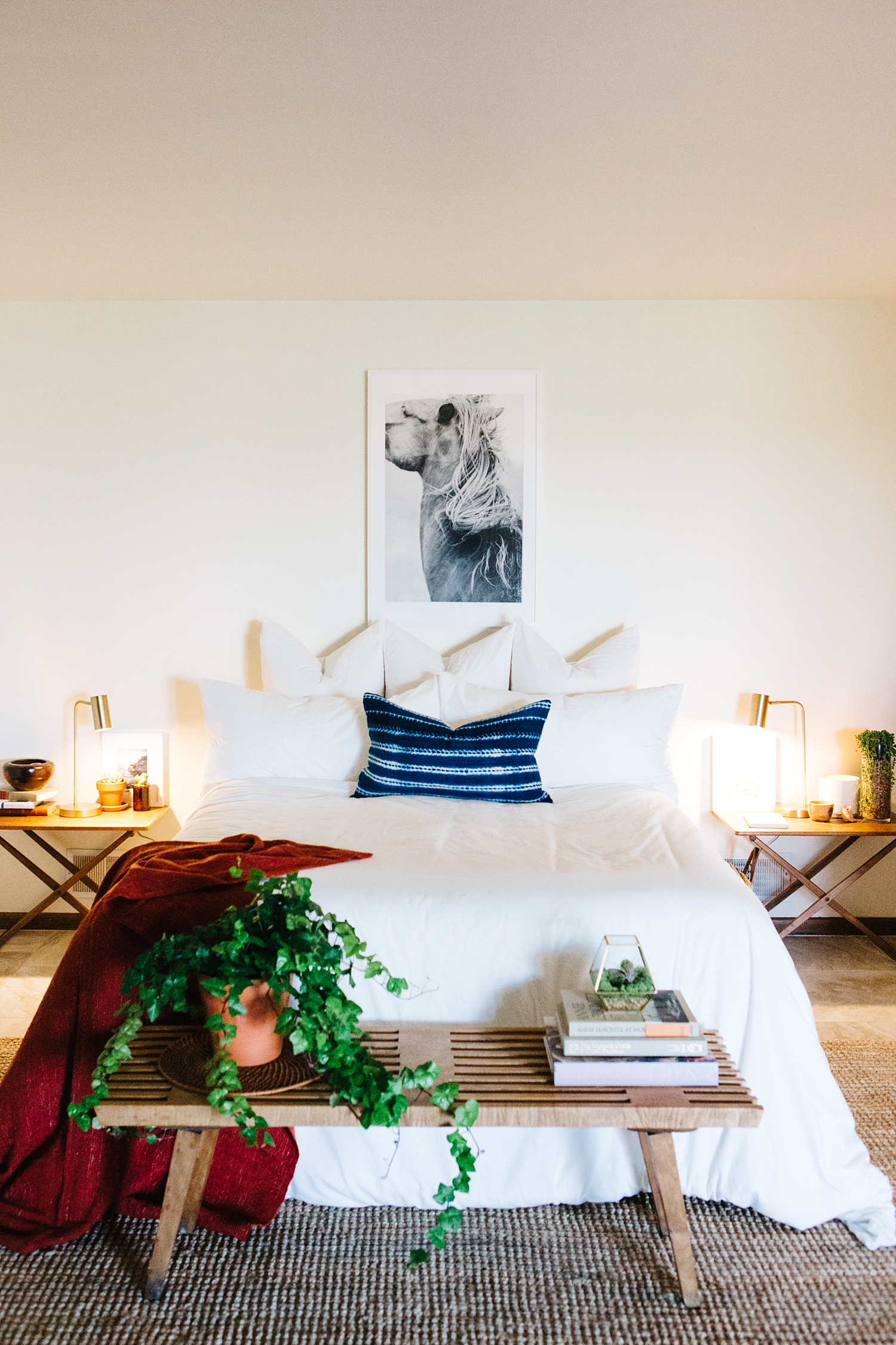 It's all about symmetry . The fine art giclee equine print anchors the mid-century bedside tables, bed, and bench together in order to draw the eye in. Forgoing a headboard keeps the space looking Scandinavian while the abundance of pillows provide a comfy Bohemian nest vibe.