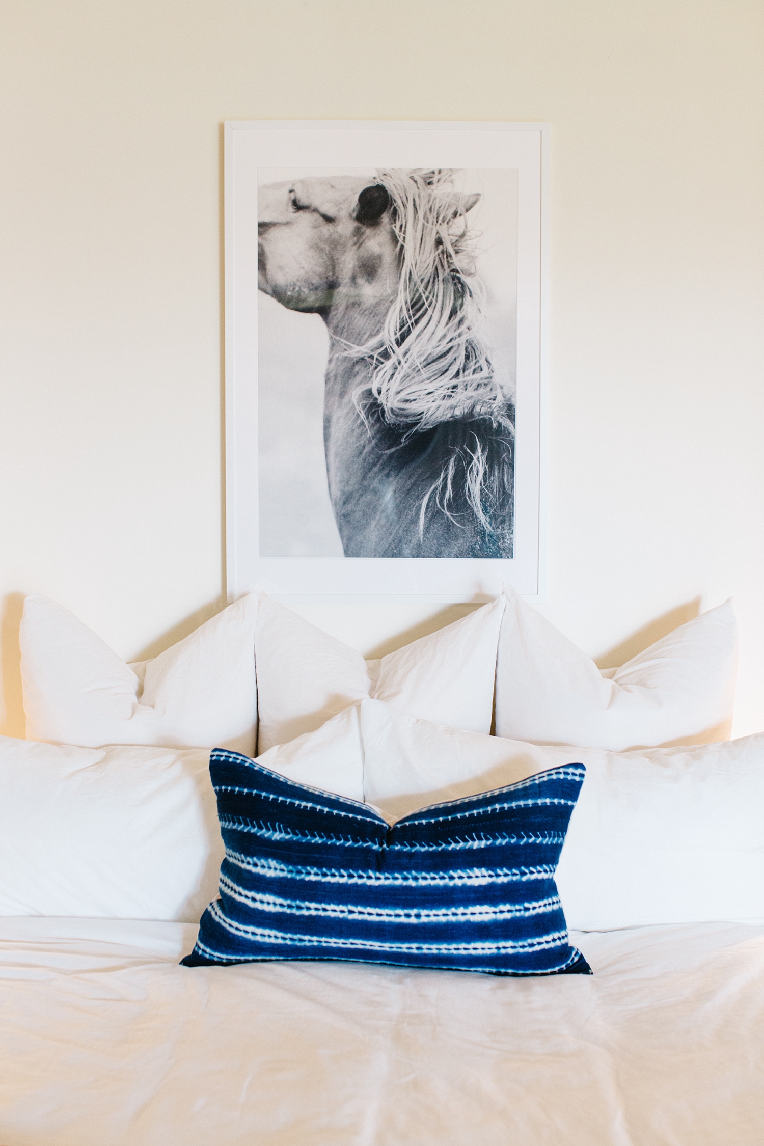 Possessing a powerful intensity, the authentic African indigo mudcloth pillow and the black and white print are the pieces I chose to really define this space. The white frame melts into the wall bringing the potency of the black and white equine print to the forefront. The strong shade of indigo of the lumbar pillow becomes an additional focal point, with the pattern elevating it to textile art.