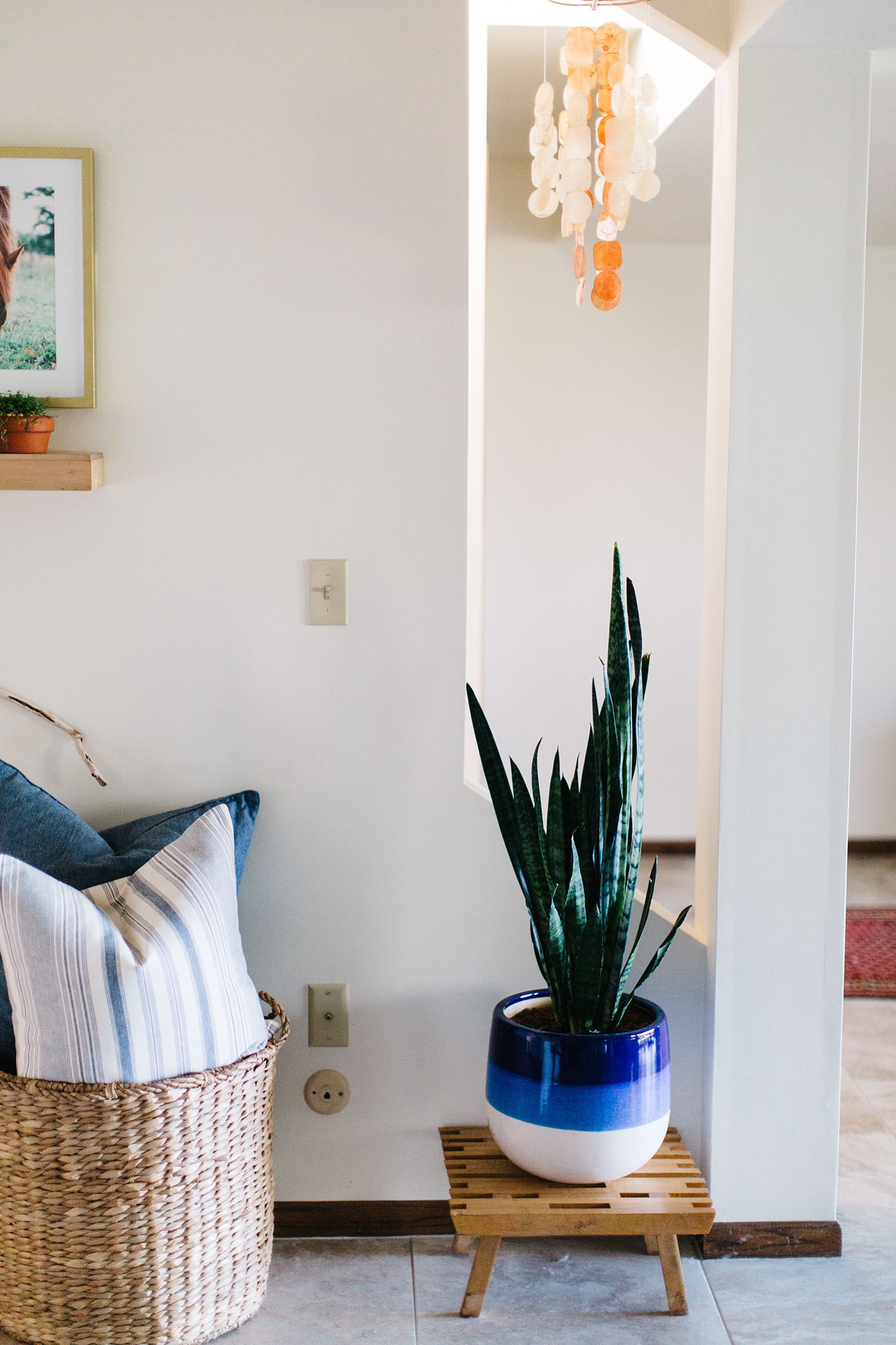 This Capiz Shell wind chime from the Philippines was the perfect accent in this space. By positioning it in this little nook, it defines the area and plays well with the terracotta and blue ceramic pots that the houseplants are in. Hanging it above the snake plant (which is an excellent low maintenance air purifier) allows me to play with shape and texture within the room.
