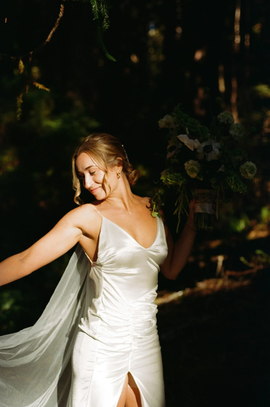 Bride framed by florals and light, skin-focused bridal makeup designed for photography and natural movement.
