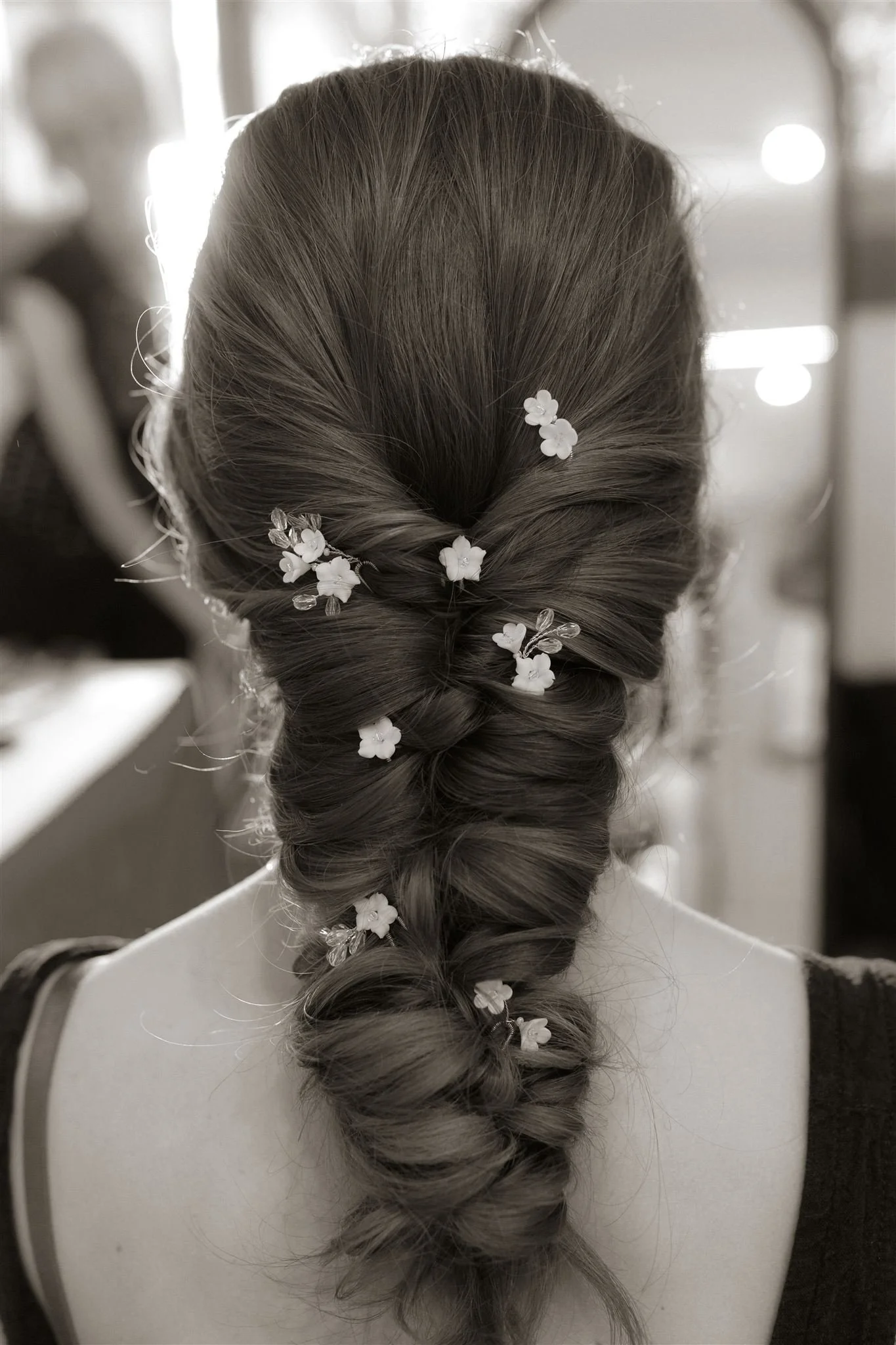 Bride from behind showing wedding dress details and softly styled hair, skin-focused bridal makeup in outdoor light.