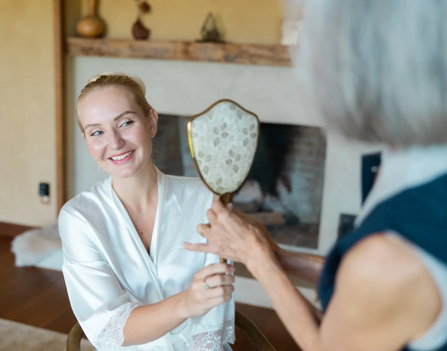 Smiling bride looking at her bridal makeup in a hand mirror