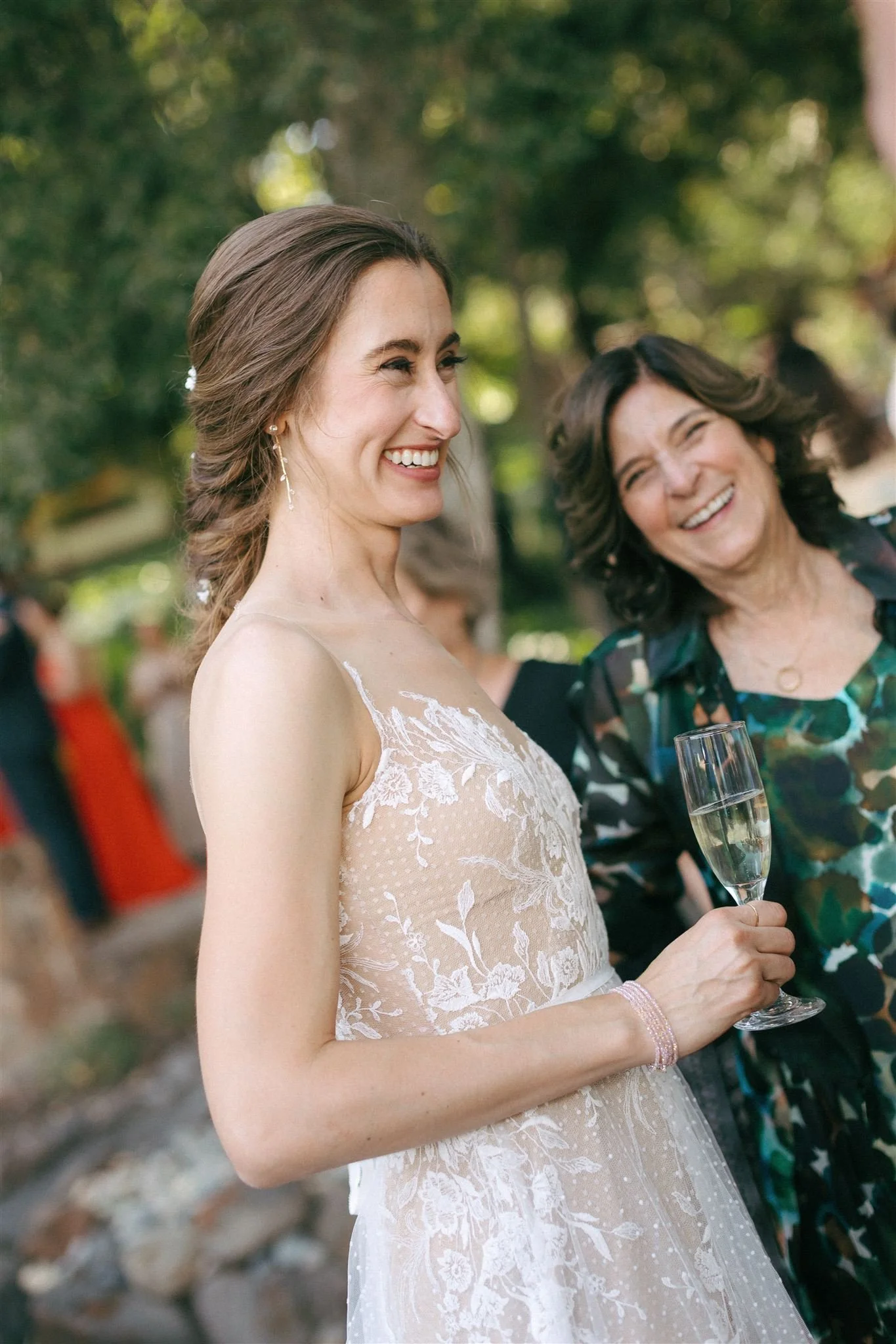 Bride smiling during outdoor wedding celebration, calm radiant bridal makeup and softly styled hair.