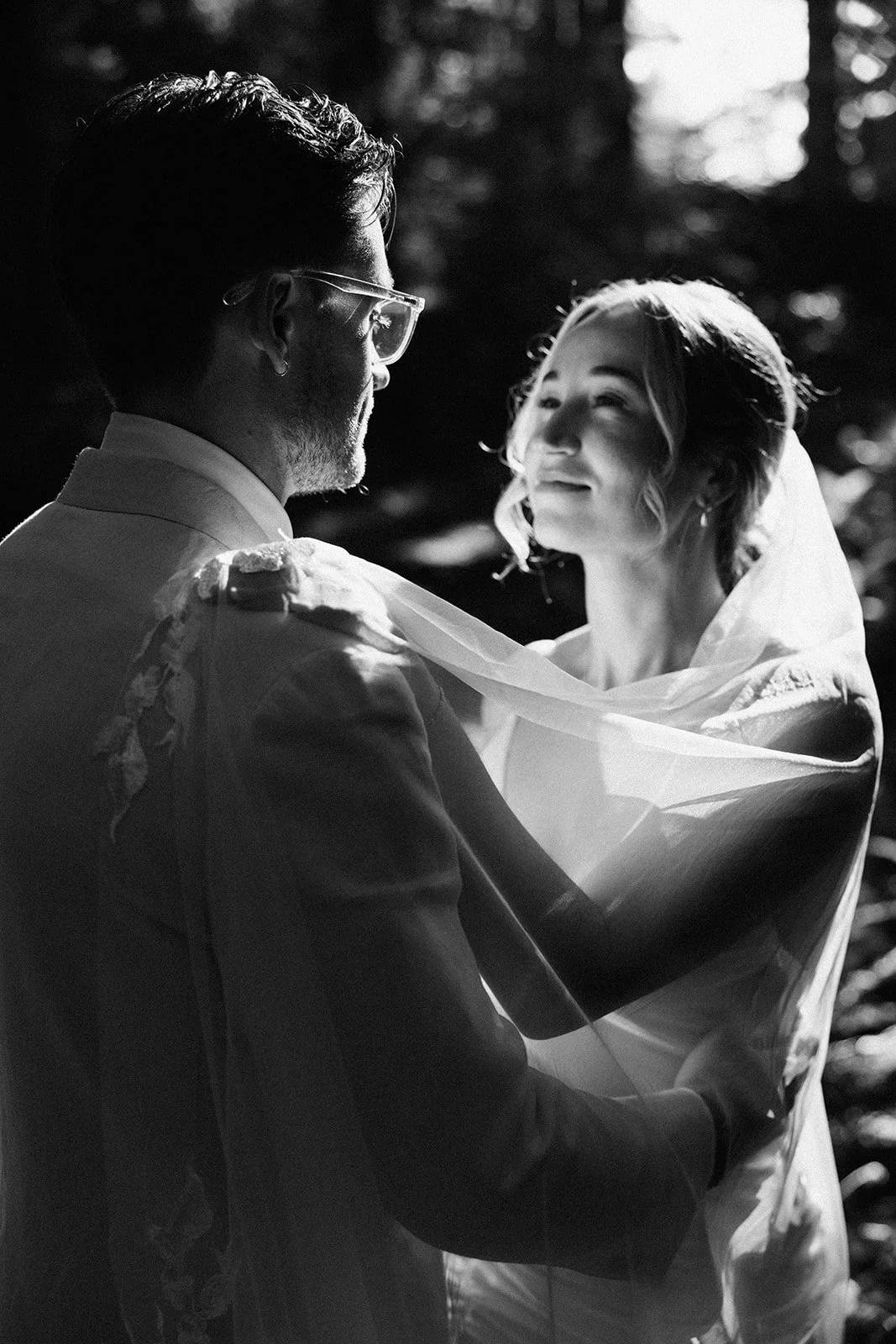Bride and groom sharing a quiet ceremony moment, soft glamour bridal makeup photographed in black and white.