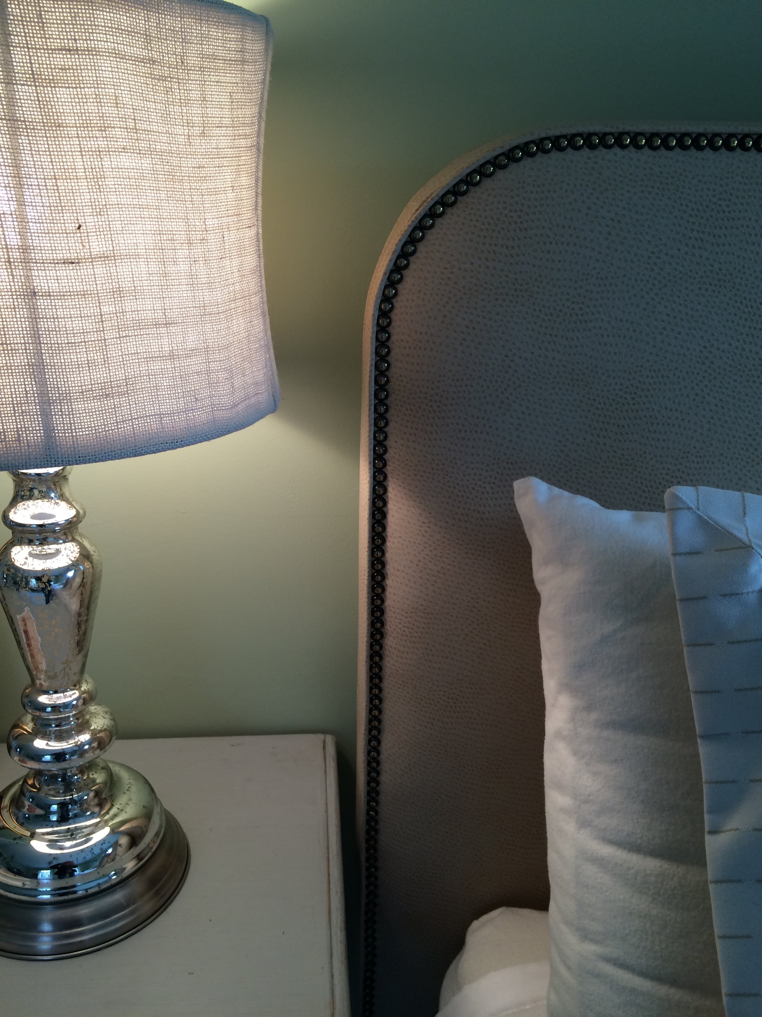 Detail of a faux leather headboard with nailhead detailing.