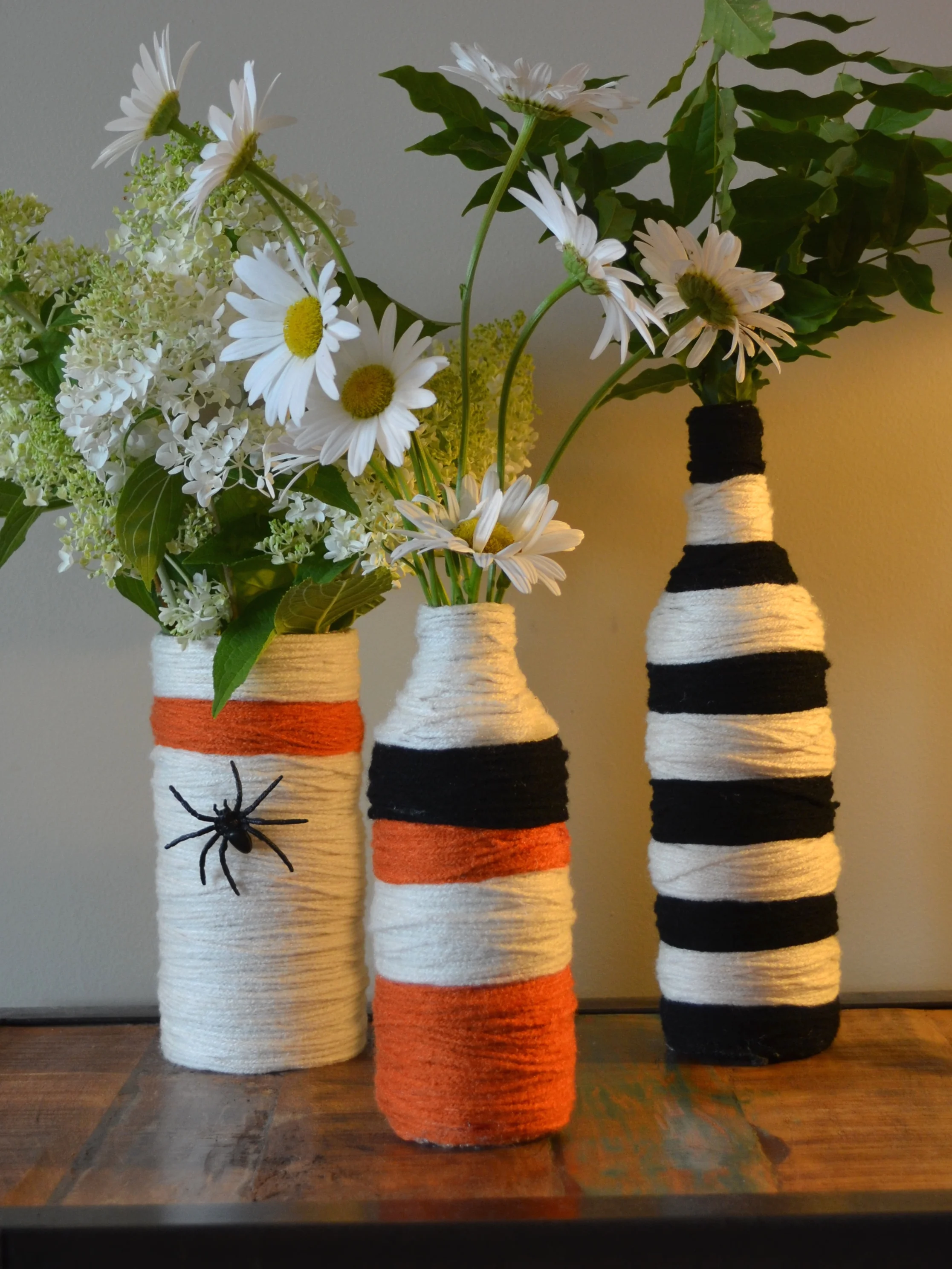 Don't forget the flowers! These Halloween craft recycled bottles and jars are so fun to make. I just used yarns and a hot glue gun. If you are going to a party -- it makes a great gift and some awesome decorations.