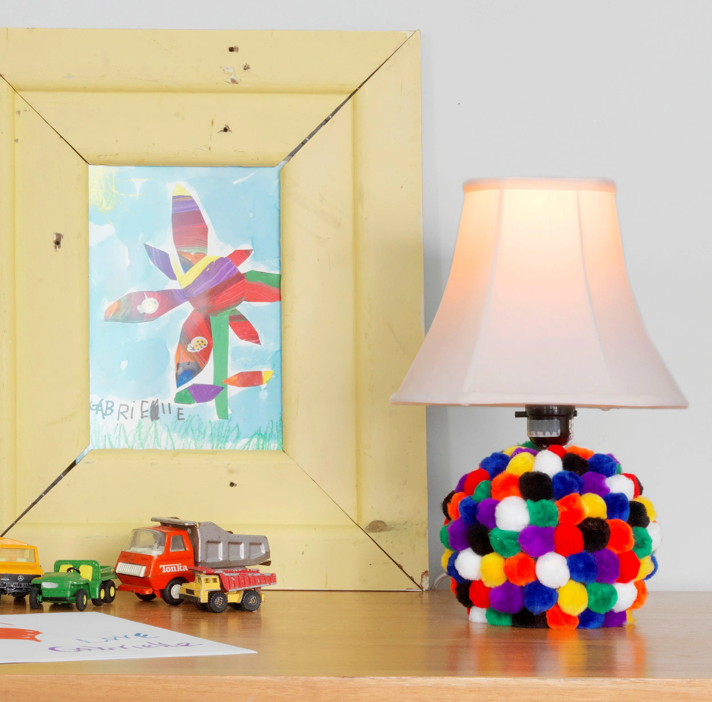 Mix a second hand store lamp with some colorful pom poms— and voilia! Instant happy lamp for the kids room!