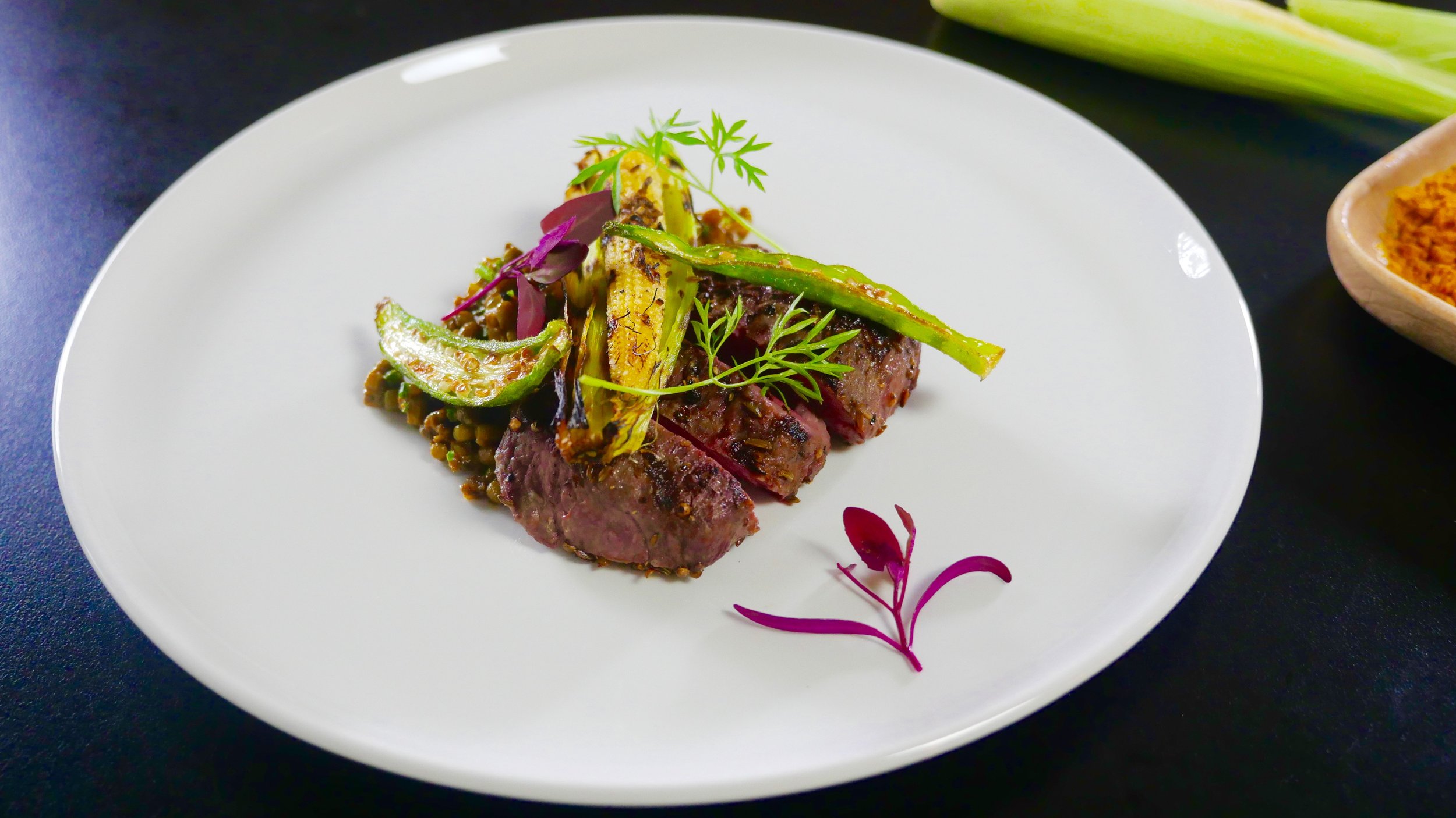 WHOLE SPICE CRUSTED LAMB LOIN, MUNG DAL, BABY CORN IN HUSK AND ORACH MICRO HERB.