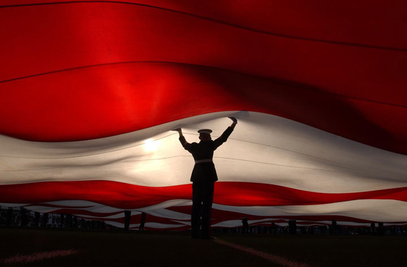  A Marine holds up a huge flag during the singing of the national anthem at the AFC Championship game between The Oakland Raiders and Tennessee Titans at Network Associates Coliseum in Oakland, California. January 12, 2003 