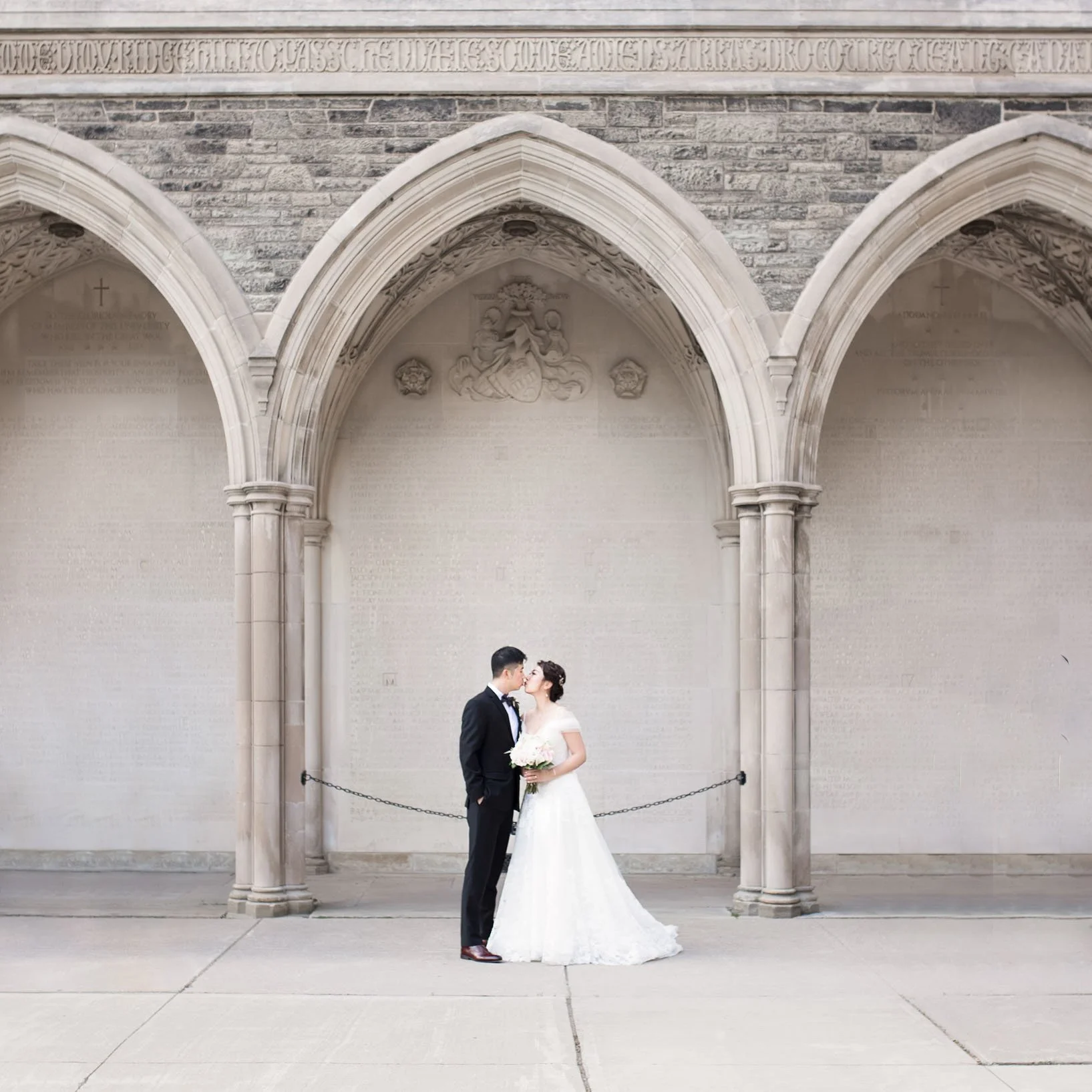 Cinematic wide shot of a bride and groom at the University of Toronto stone arches in Toronto, Ontario