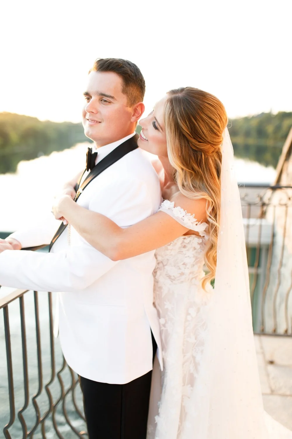 Bride embracing groom from behind during sunset wedding portraits overlooking the river at Cambridge Mill in Cambridge, Ontario