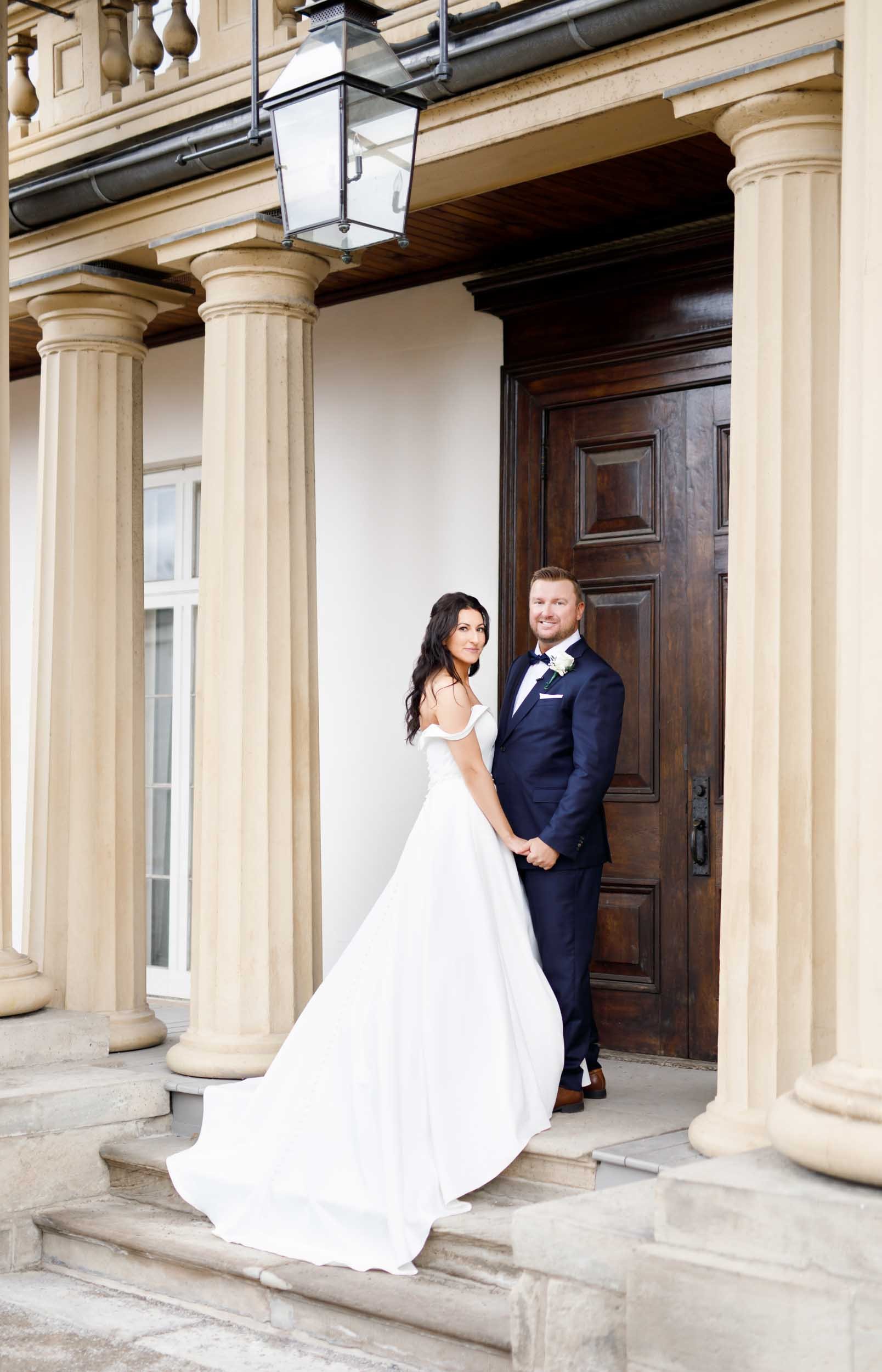 Bride and groom portrait between neoclassical columns at Dundurn Castle