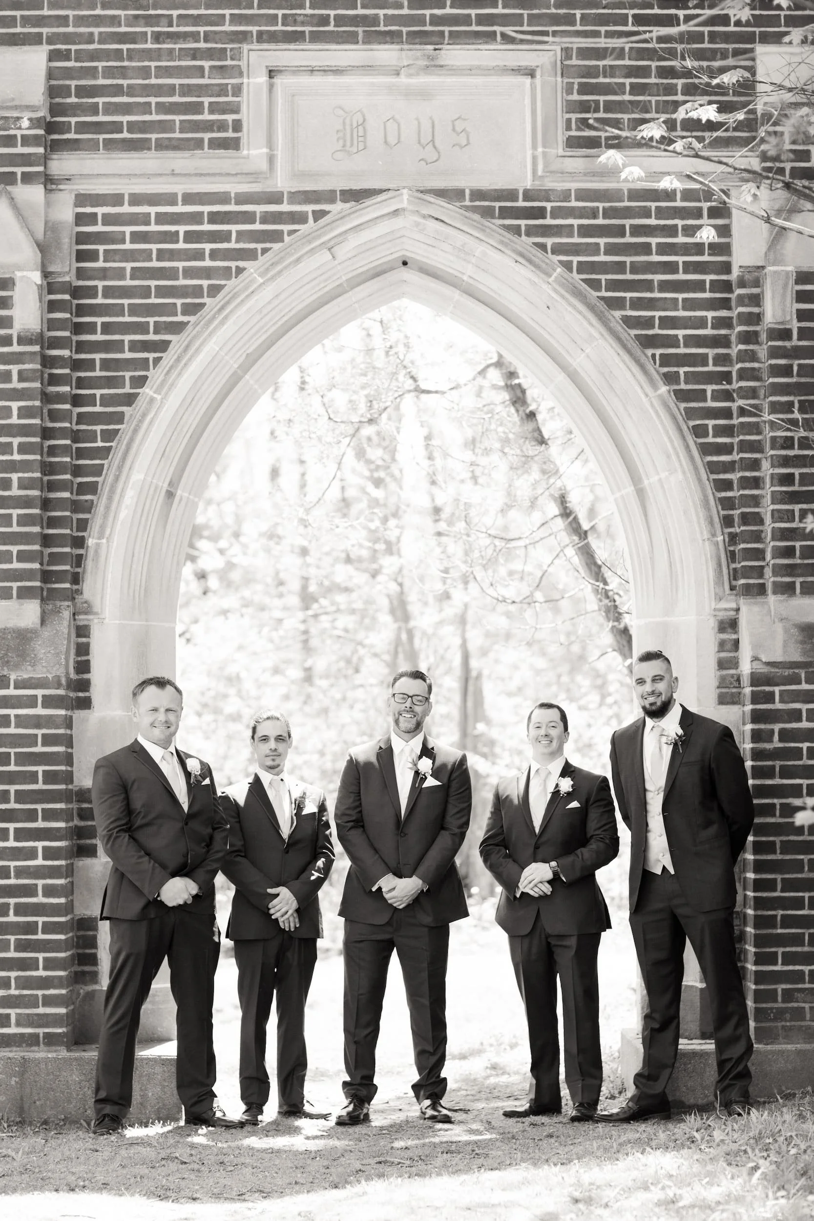 Groomsmen portrait beneath Gothic arch at Guild Inn Estate
