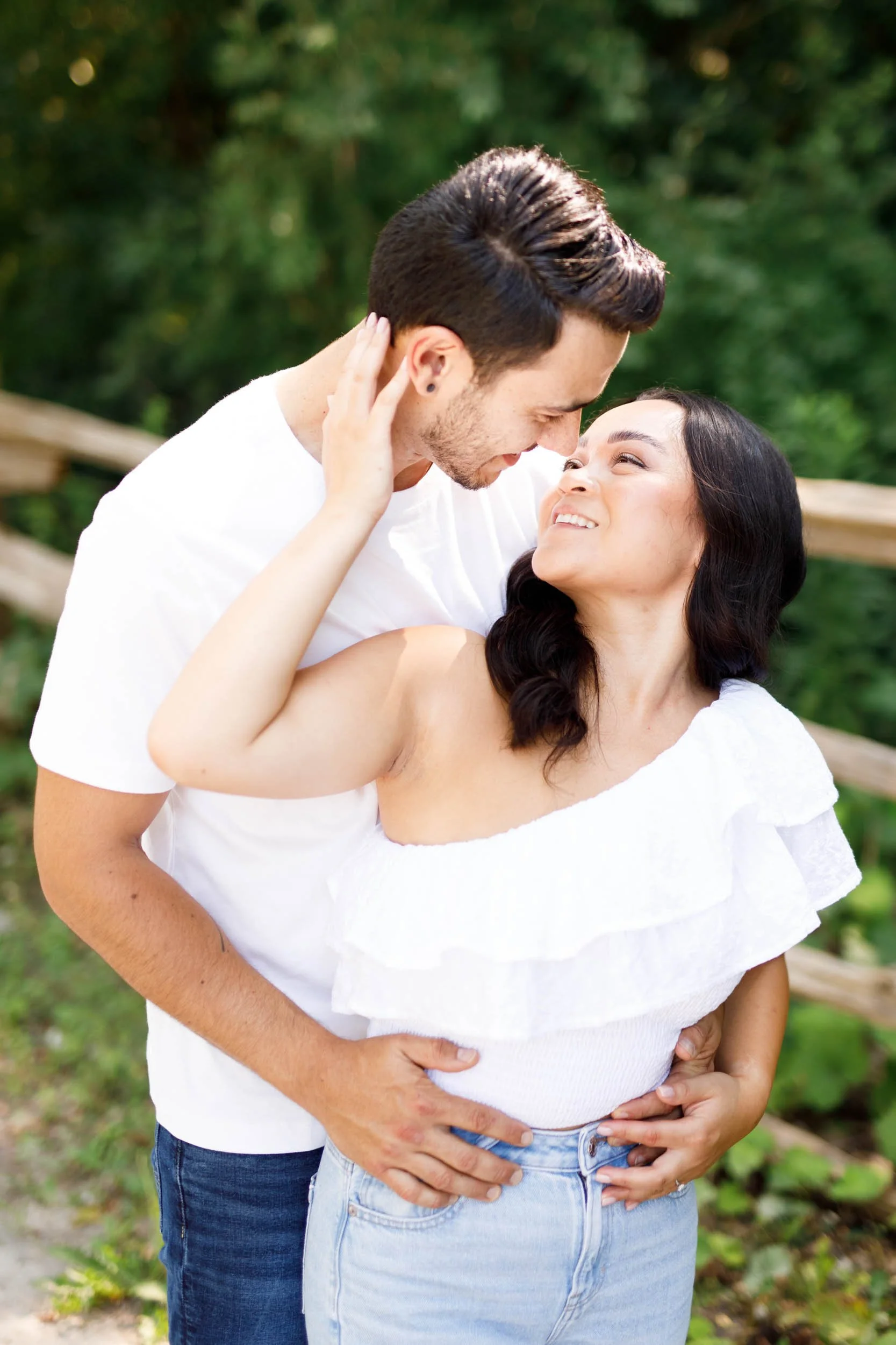 Romantic close up of an engaged couple smiling together beside a wooden fence at Kortright Centre for Conservation