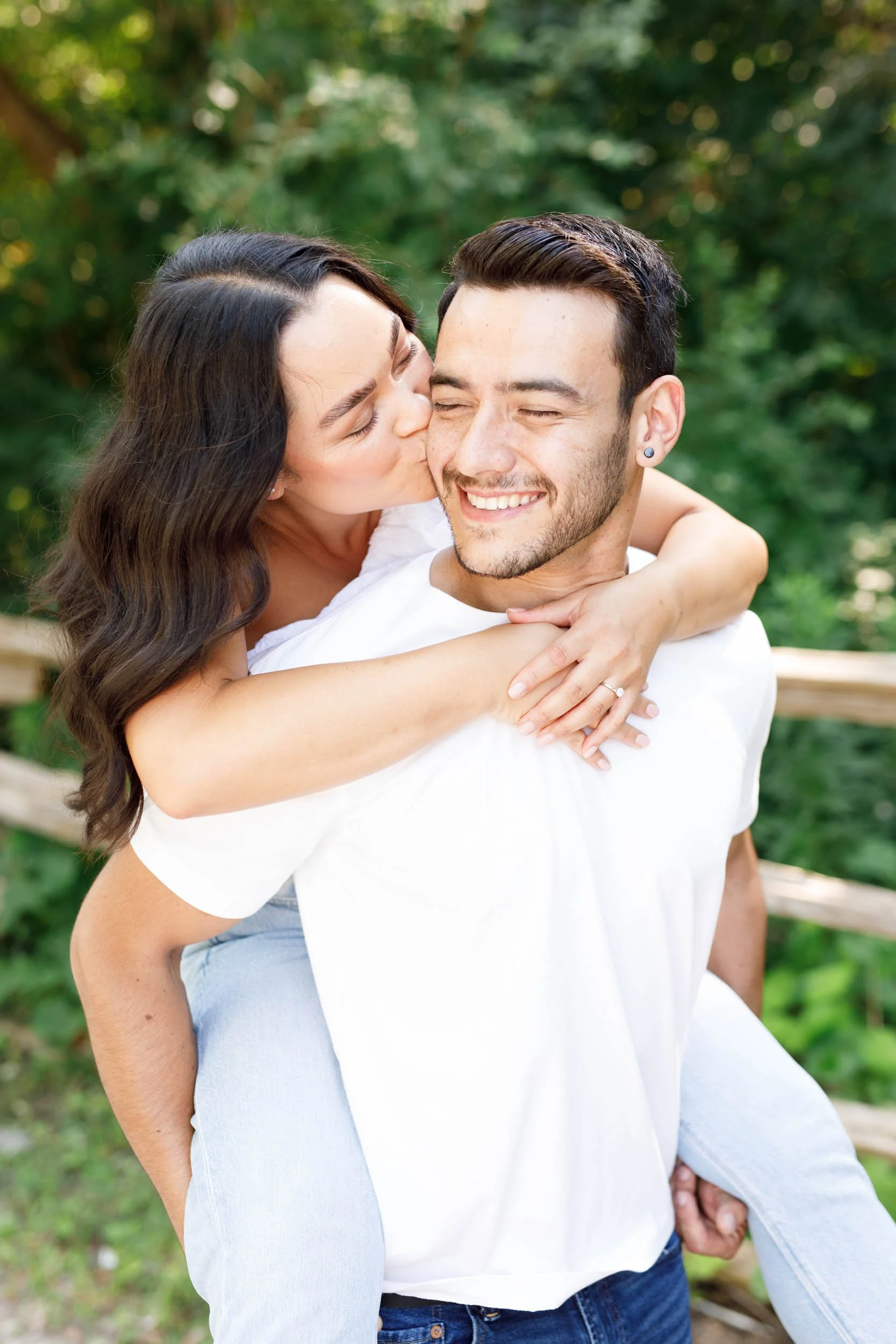 Bride to be kissing her fiancé on the cheek during a playful piggyback moment at Kortright Centre for Conservation in Woodbridge Ontario