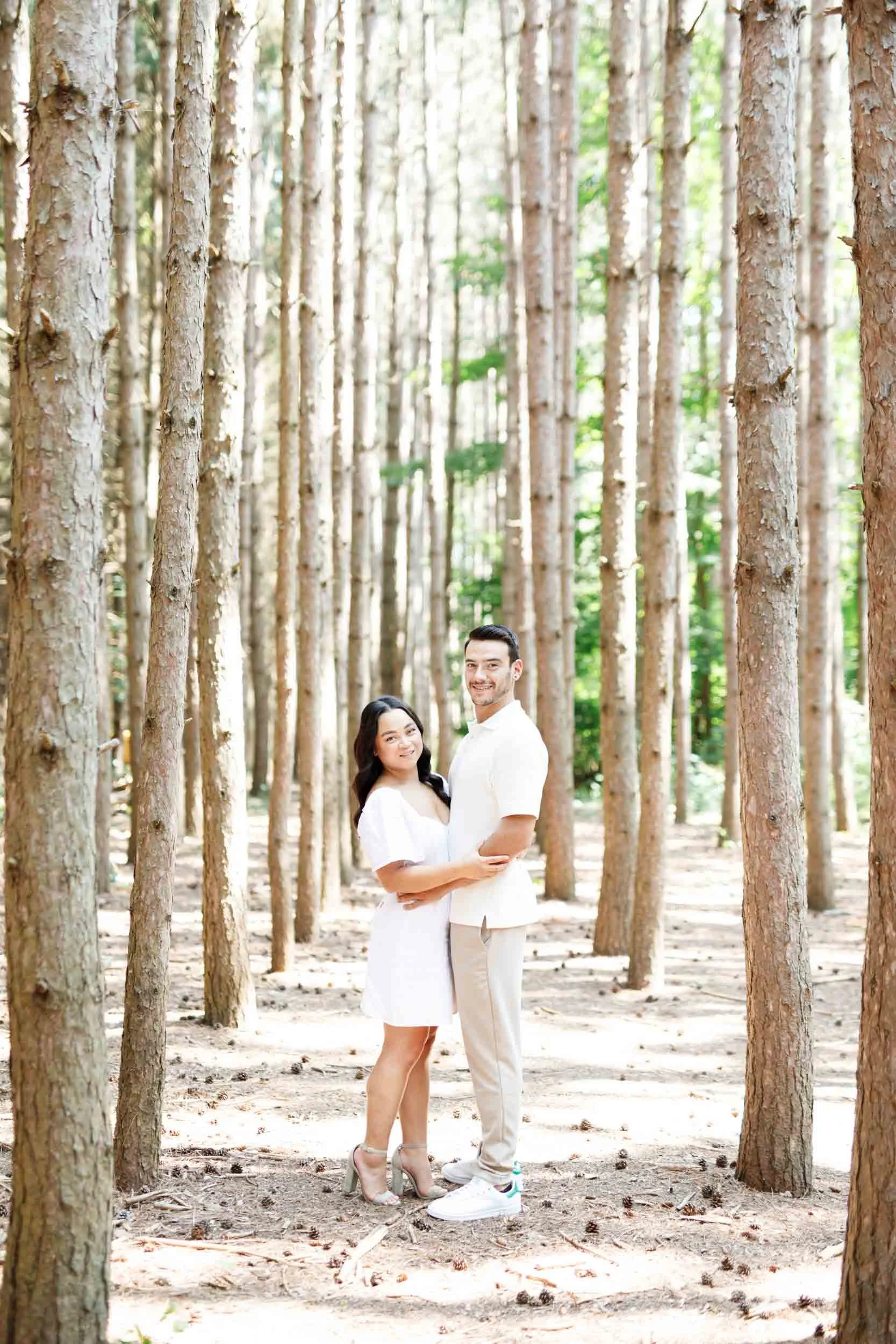 Engaged couple standing together in the tall pine forest at Kortright Centre for Conservation in Woodbridge Ontario