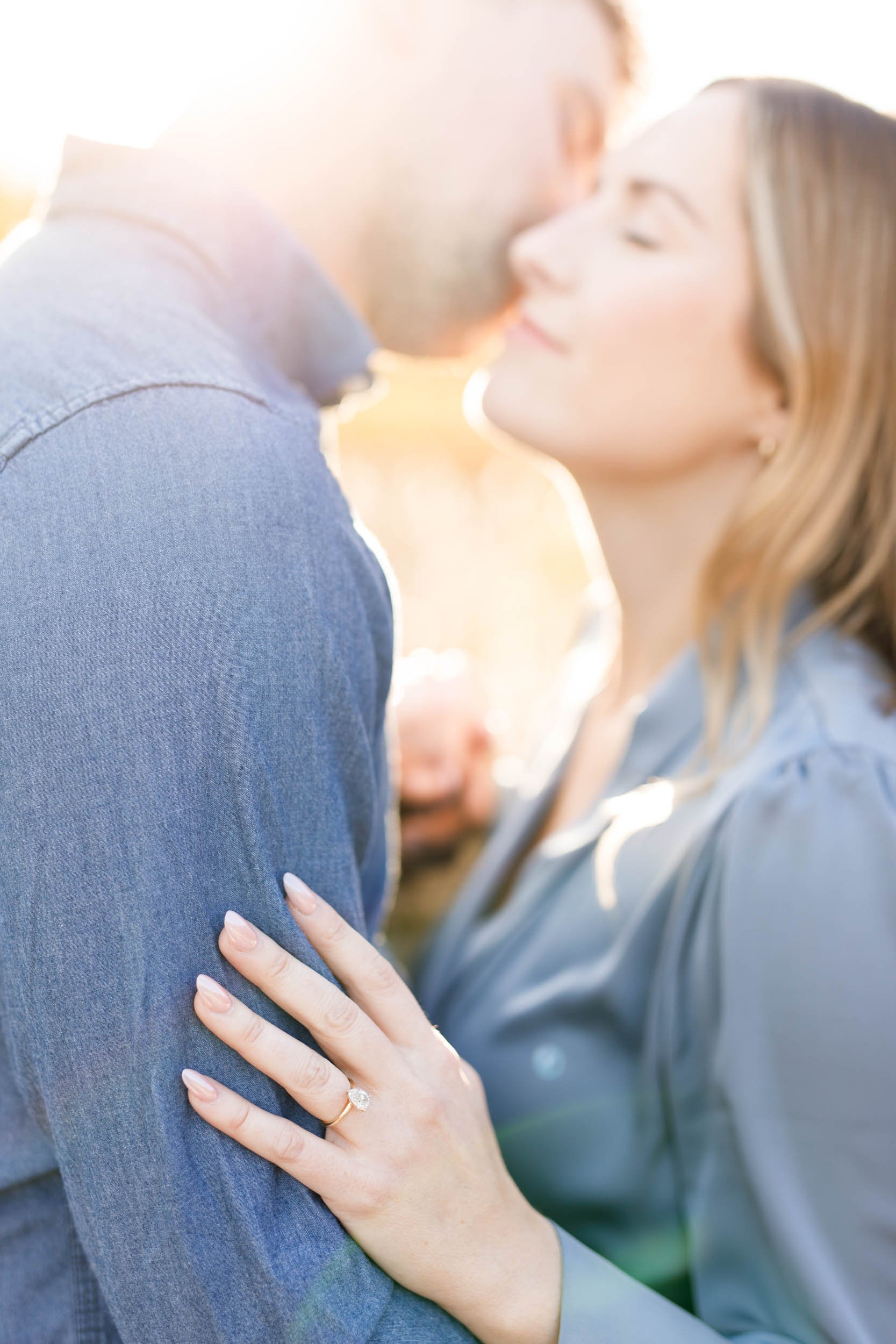 Close up of engagement ring as the bride to be rests her hand on her fiancé’s arm during sunset at Grindstone Marsh Trail