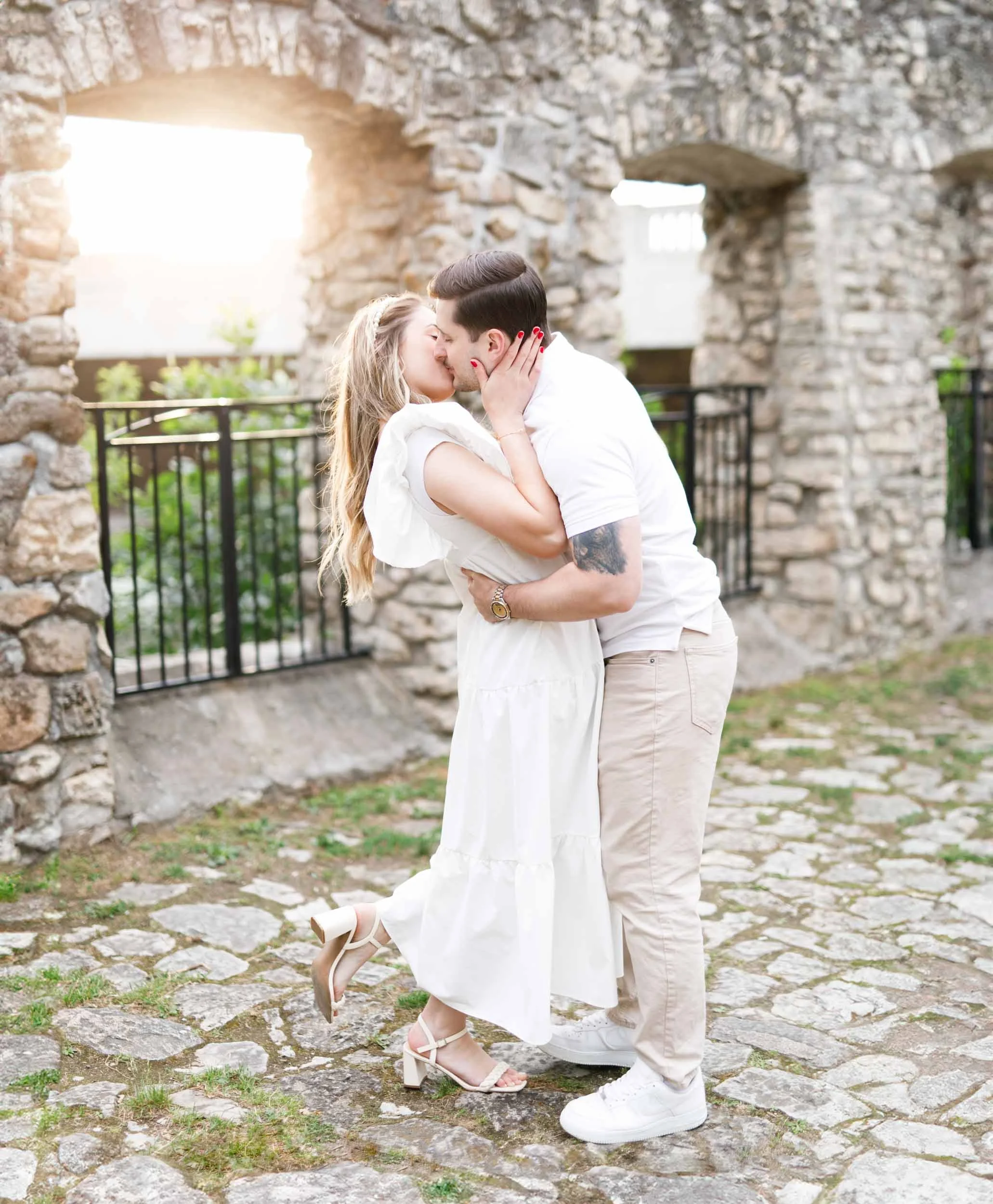 Romantic engagement portrait of a couple embracing under the stone arches at Mill Race Park in Cambridge