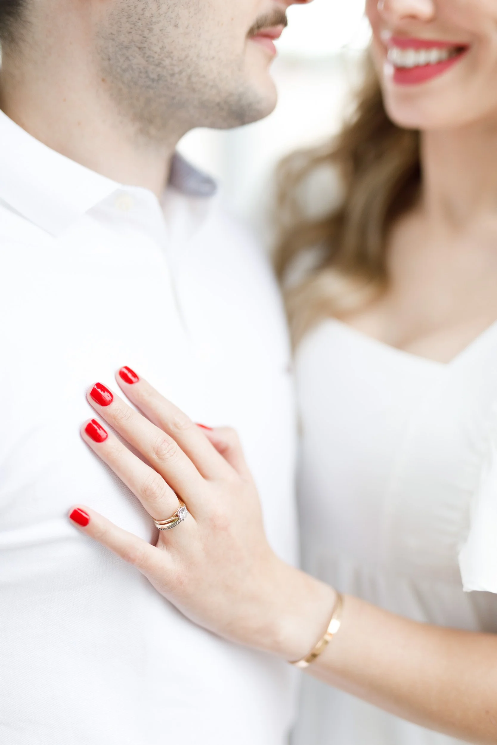 Close up of engagement ring as the bride to be rests her hand on her fiancé’s chest during their session at Mill Race Park in Cambridge