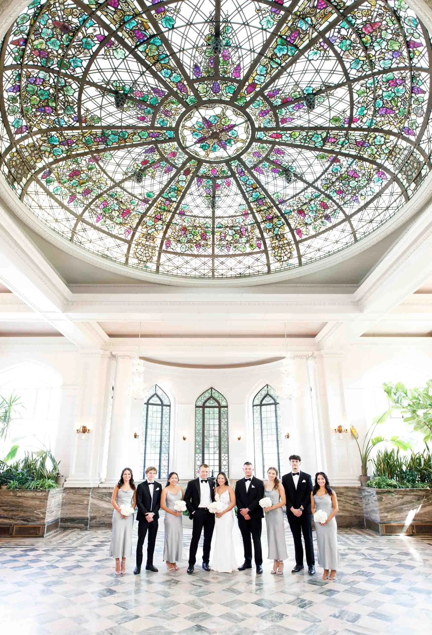 Wedding party inside Casa Loma beneath the stained glass ceiling in Toronto
