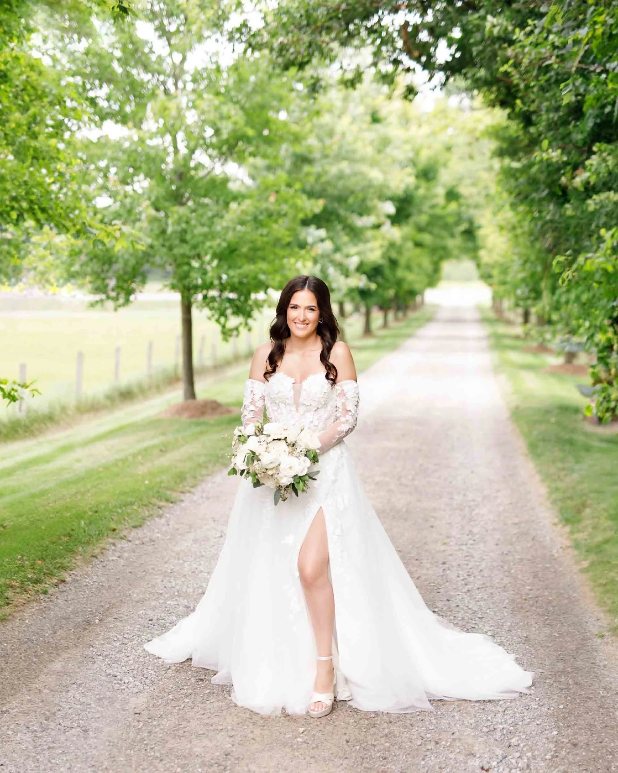 Bride walking down a tree-lined path at a Cambium Farms wedding in Alton, Ontario