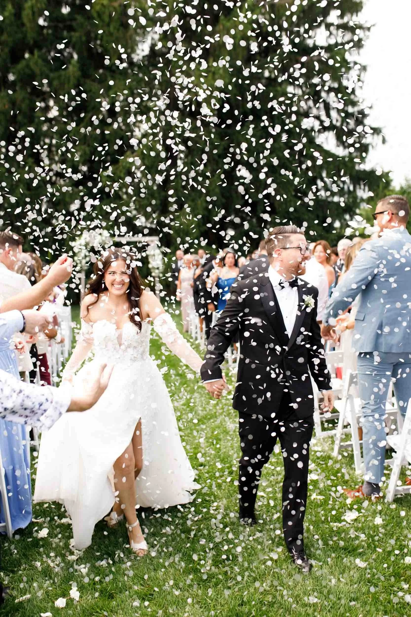 Bride and groom walking through falling confetti petals at a Cambium Farms wedding in Alton, Ontario