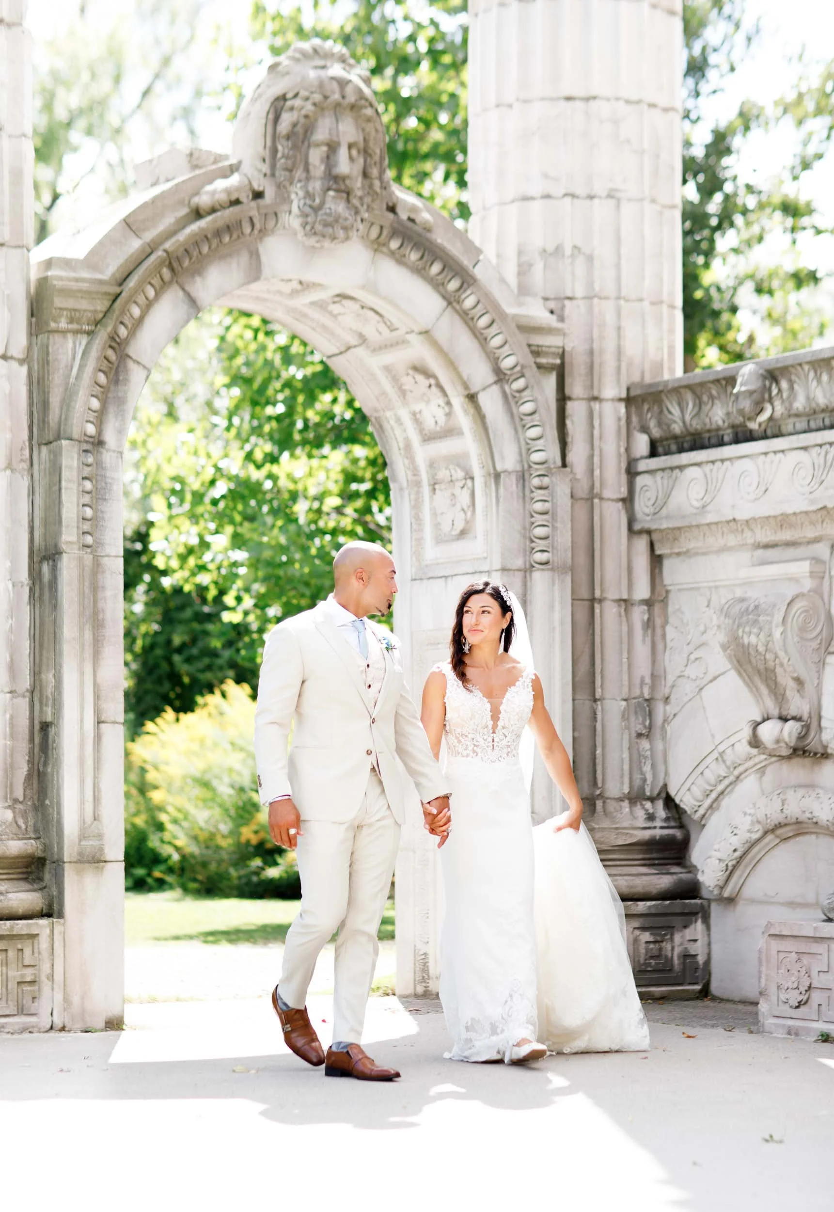 Bride and groom walking through the stone arches at the Guild Inn Estate in Scarborough