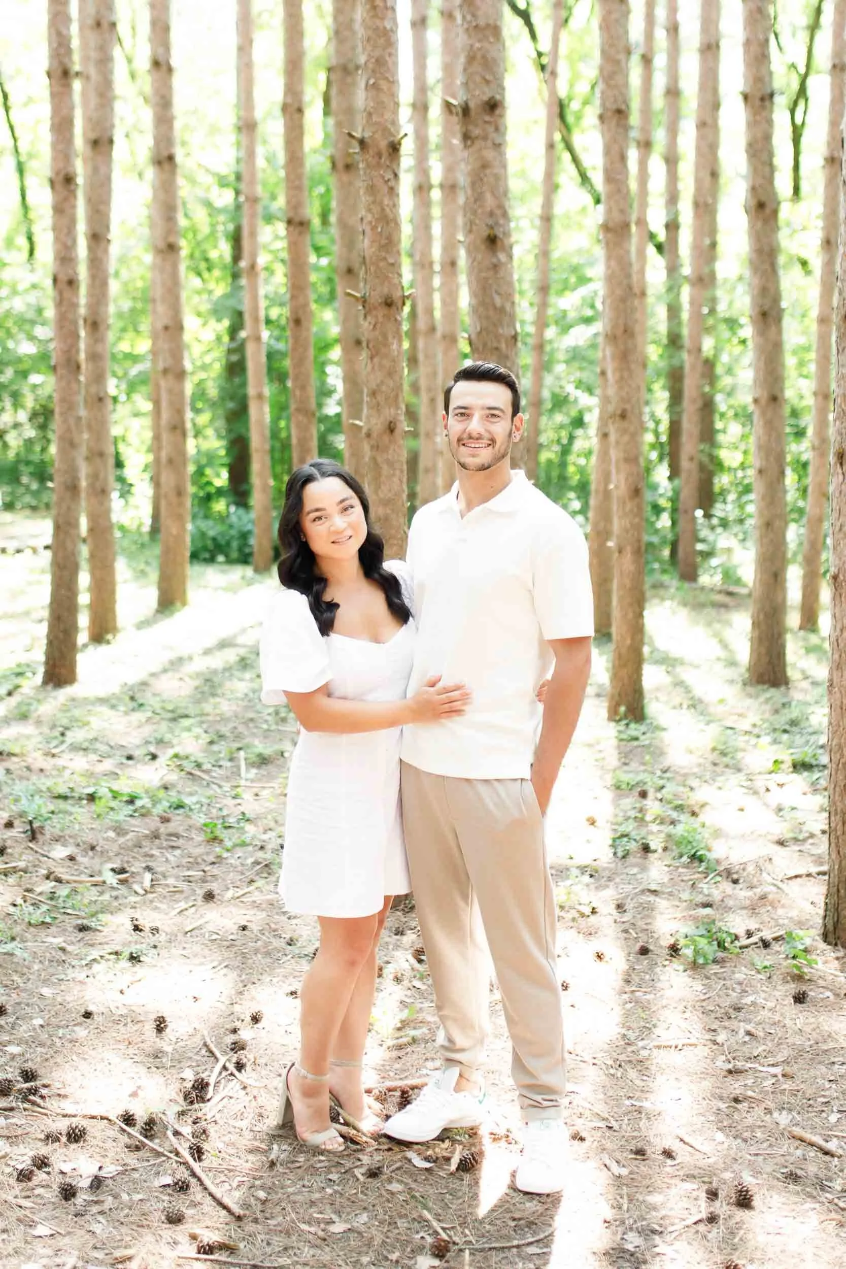 Couple posing between trees during engagement photos at Kortright Centre in Woodbridge, Ontario