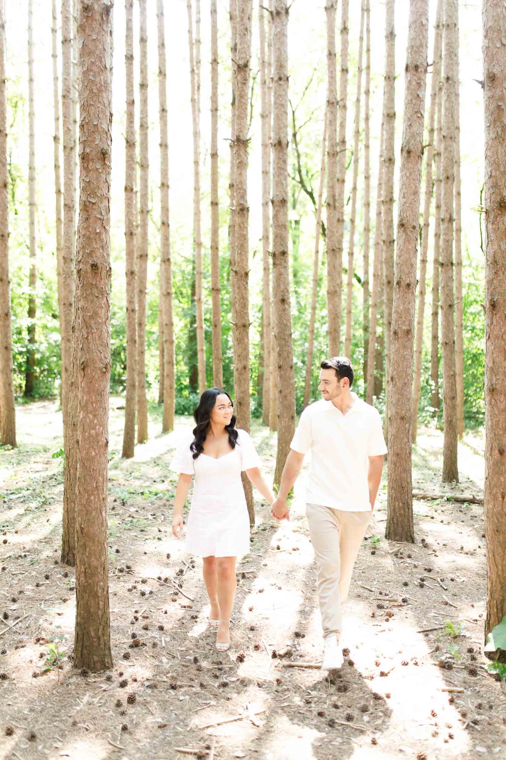Couple walking together through the forest during their Kortright Centre engagement in Woodbridge, Ontario