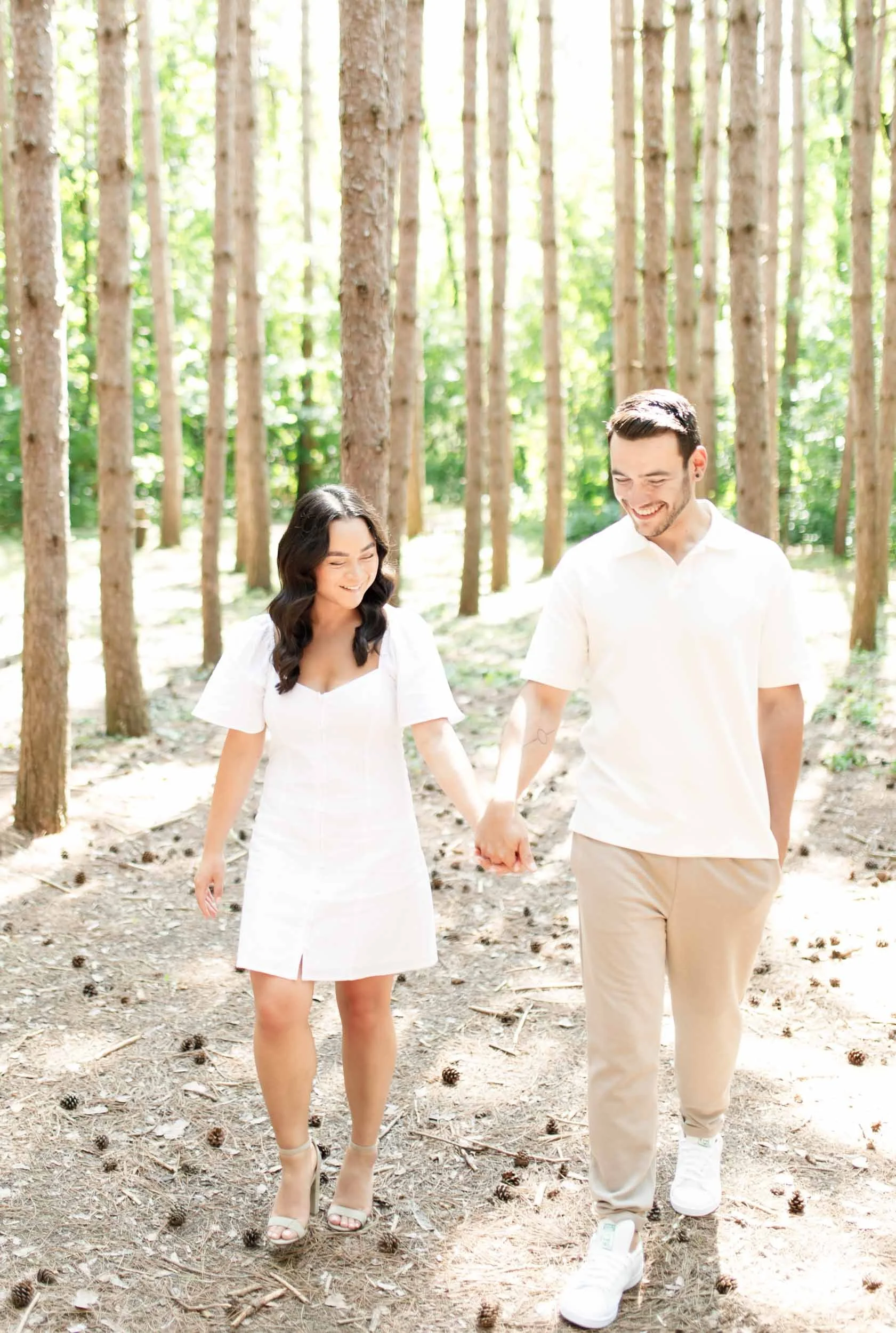 Couple holding hands while walking between trees at Kortright Centre for Conservation in Woodbridge, Ontario