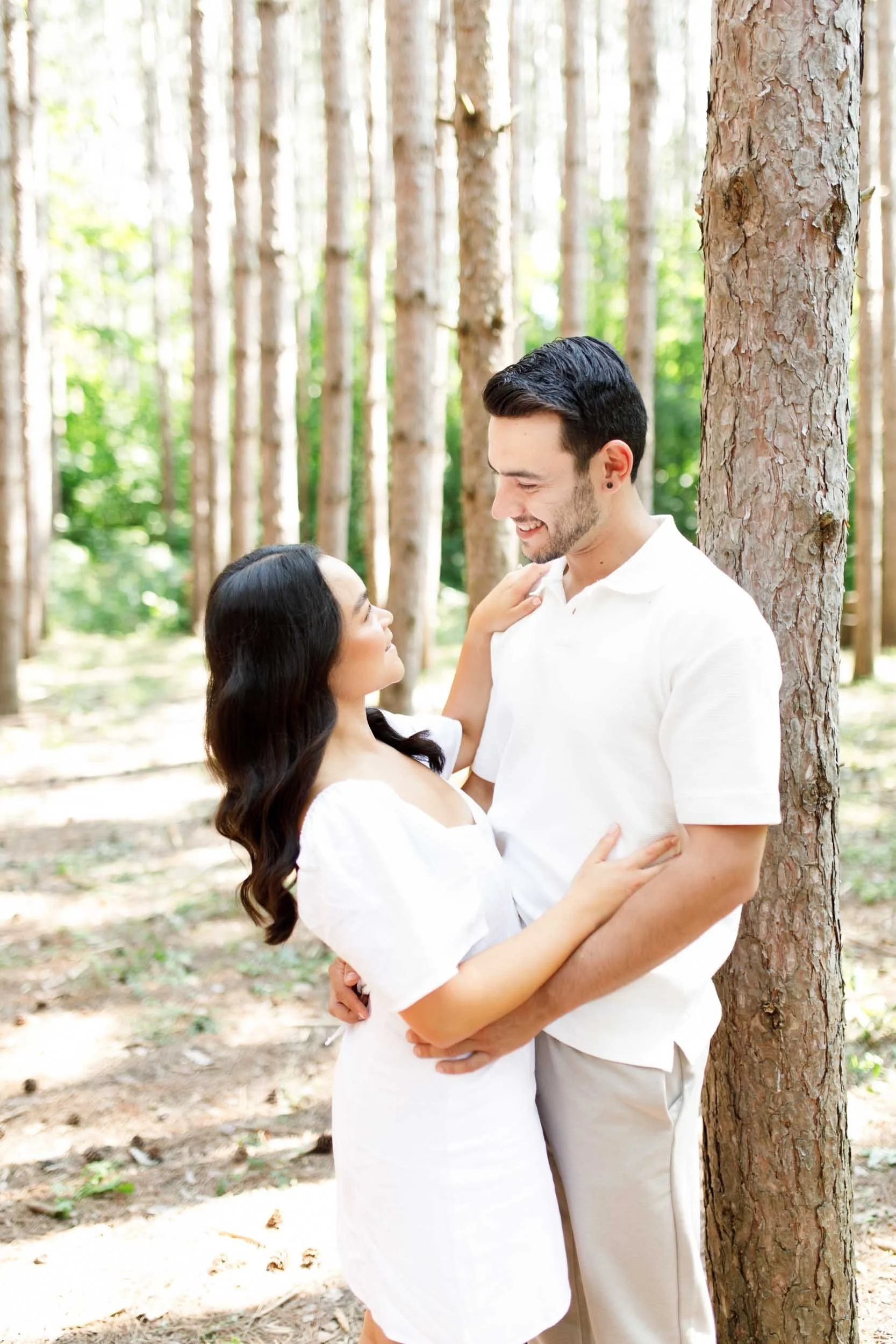 Couple hugging in the forest during engagement photos at Kortright Centre in Woodbridge, Ontario