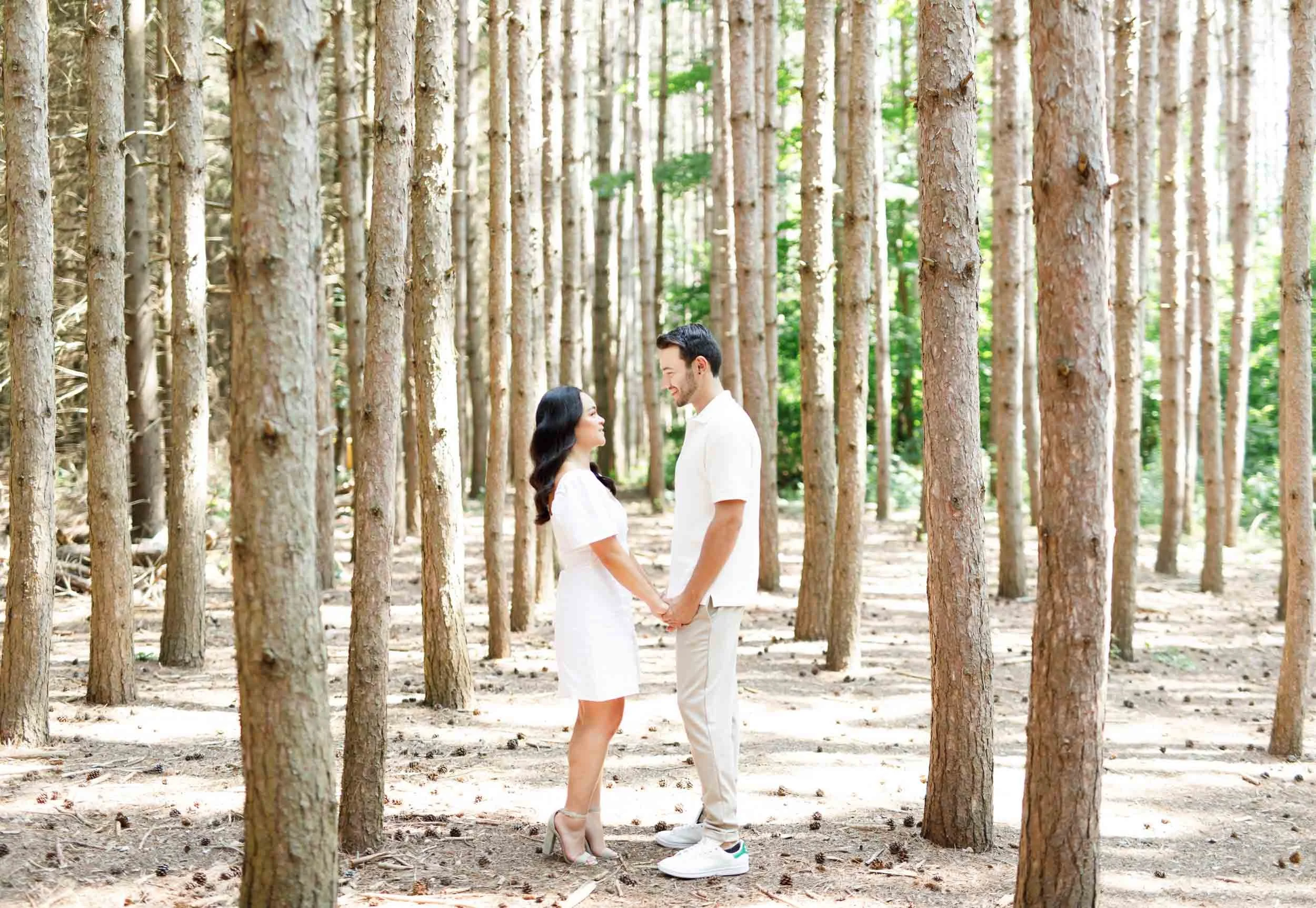 Couple holding hands in the forest during their Kortright Centre engagement session in Woodbridge, Ontario