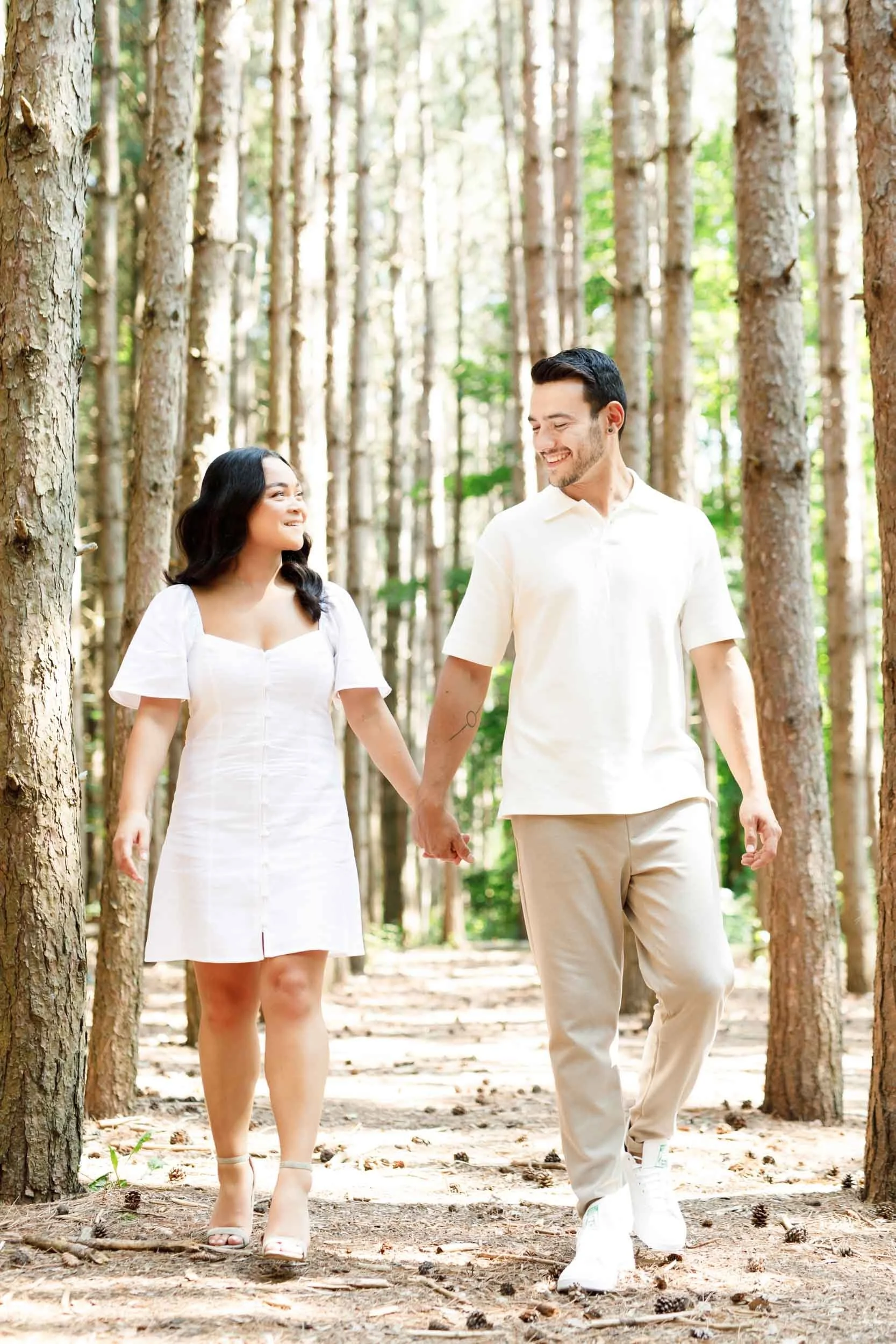 Couple walking together between trees during their Kortright Centre engagement in Woodbridge, Ontario