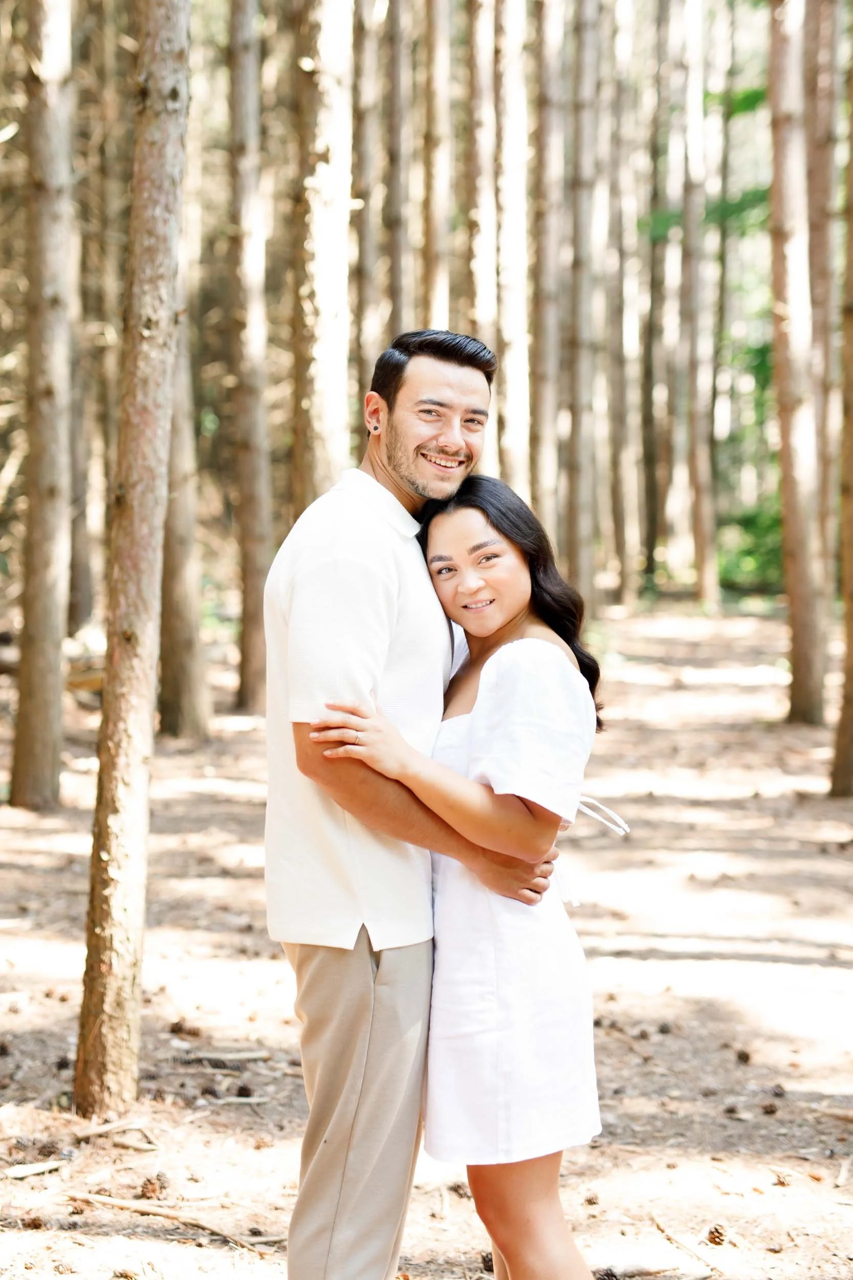 Couple hugging and smiling in the forest at Kortright Centre for Conservation in Woodbridge, Ontario
