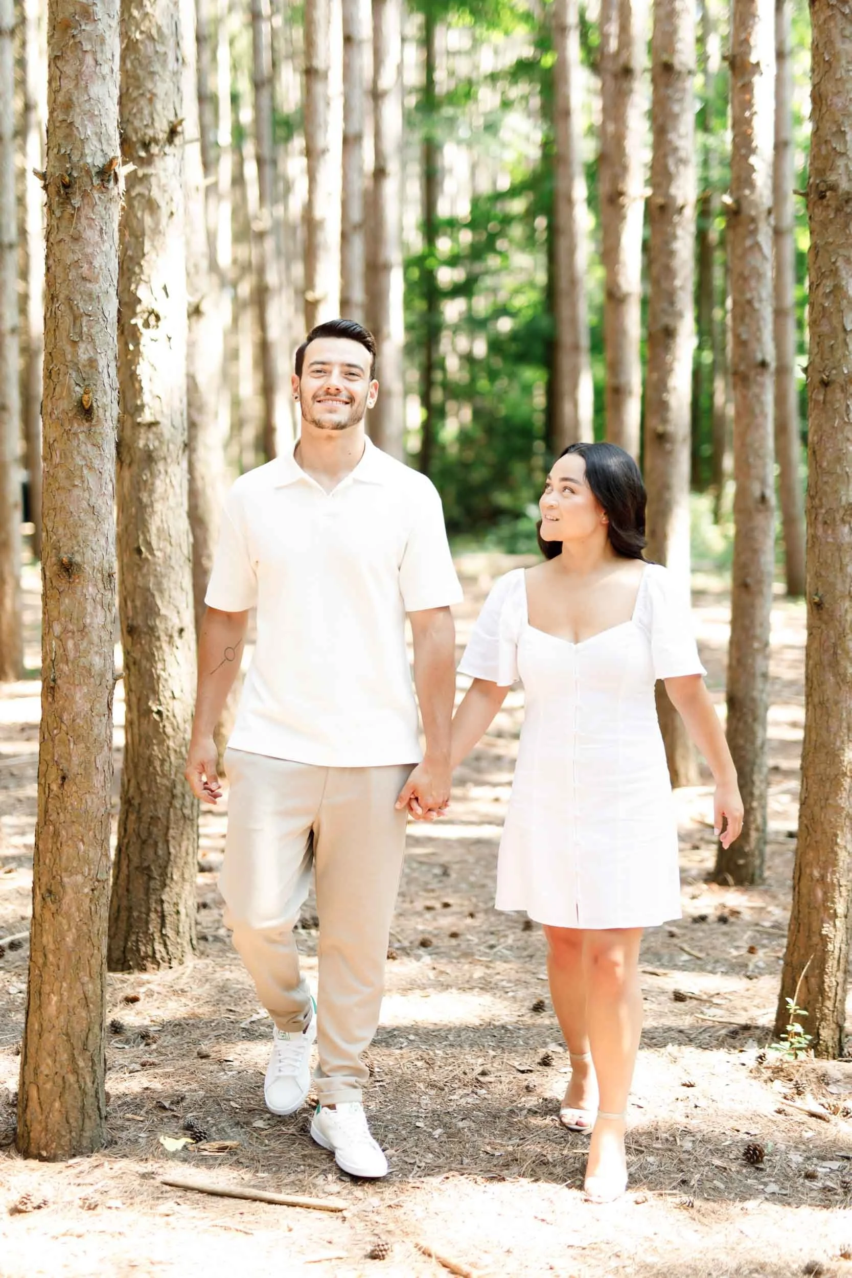 Couple walking hand in hand through trees at Kortright Centre in Woodbridge, Ontario
