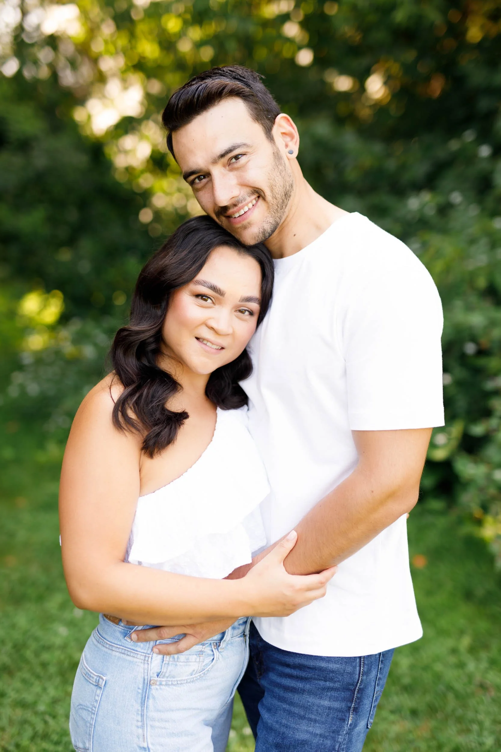 Couple hugging and smiling in a grassy meadow at Kortright Centre in Woodbridge, Ontario