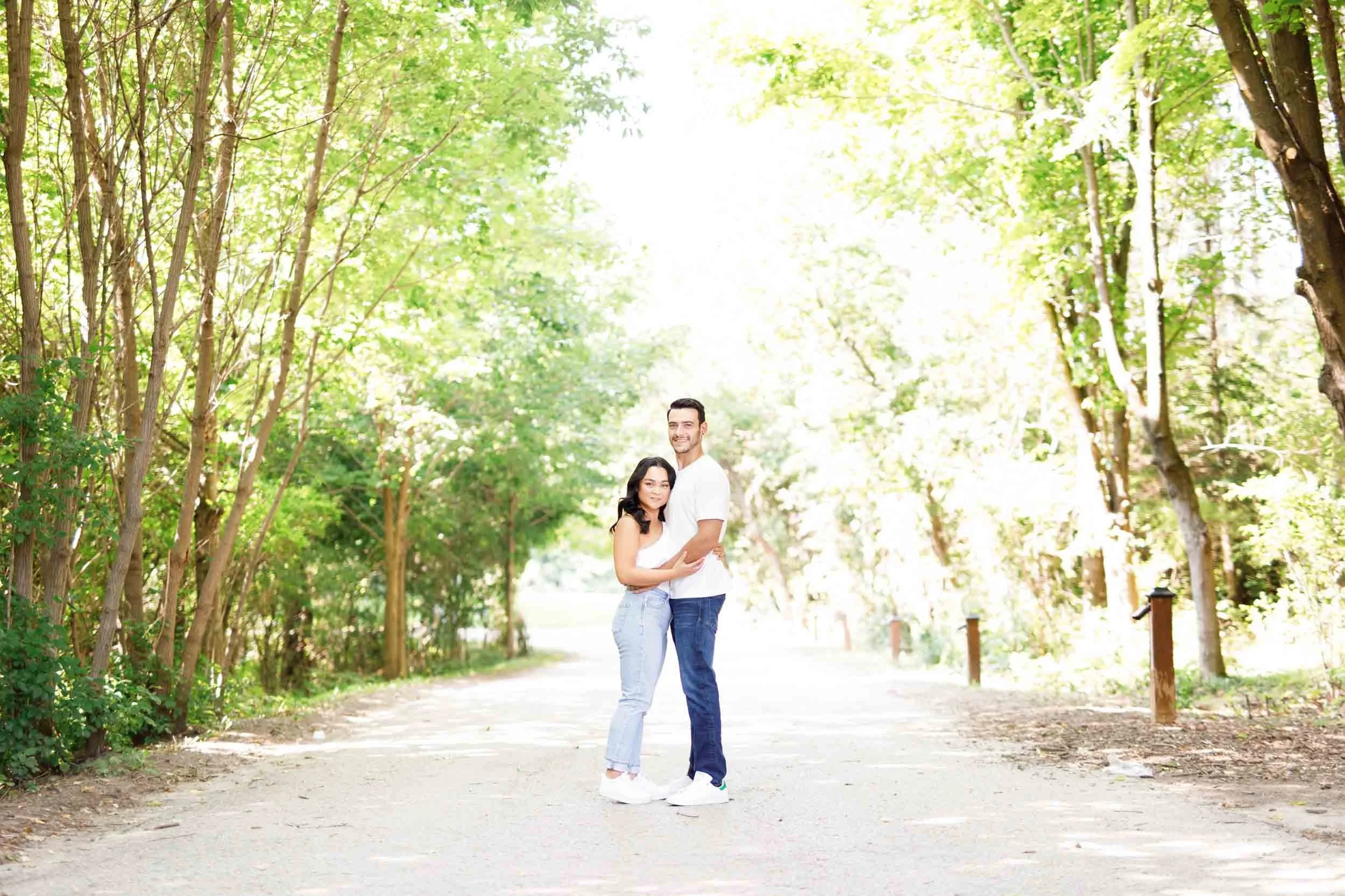 Engaged couple standing together on a tree-lined trail at Kortright Centre in Woodbridge, Ontario
