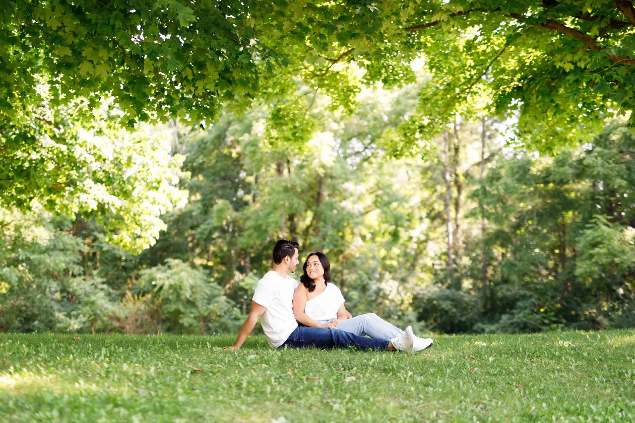 Engaged couple relaxing together under trees at Kortright Centre in Woodbridge, Ontario
