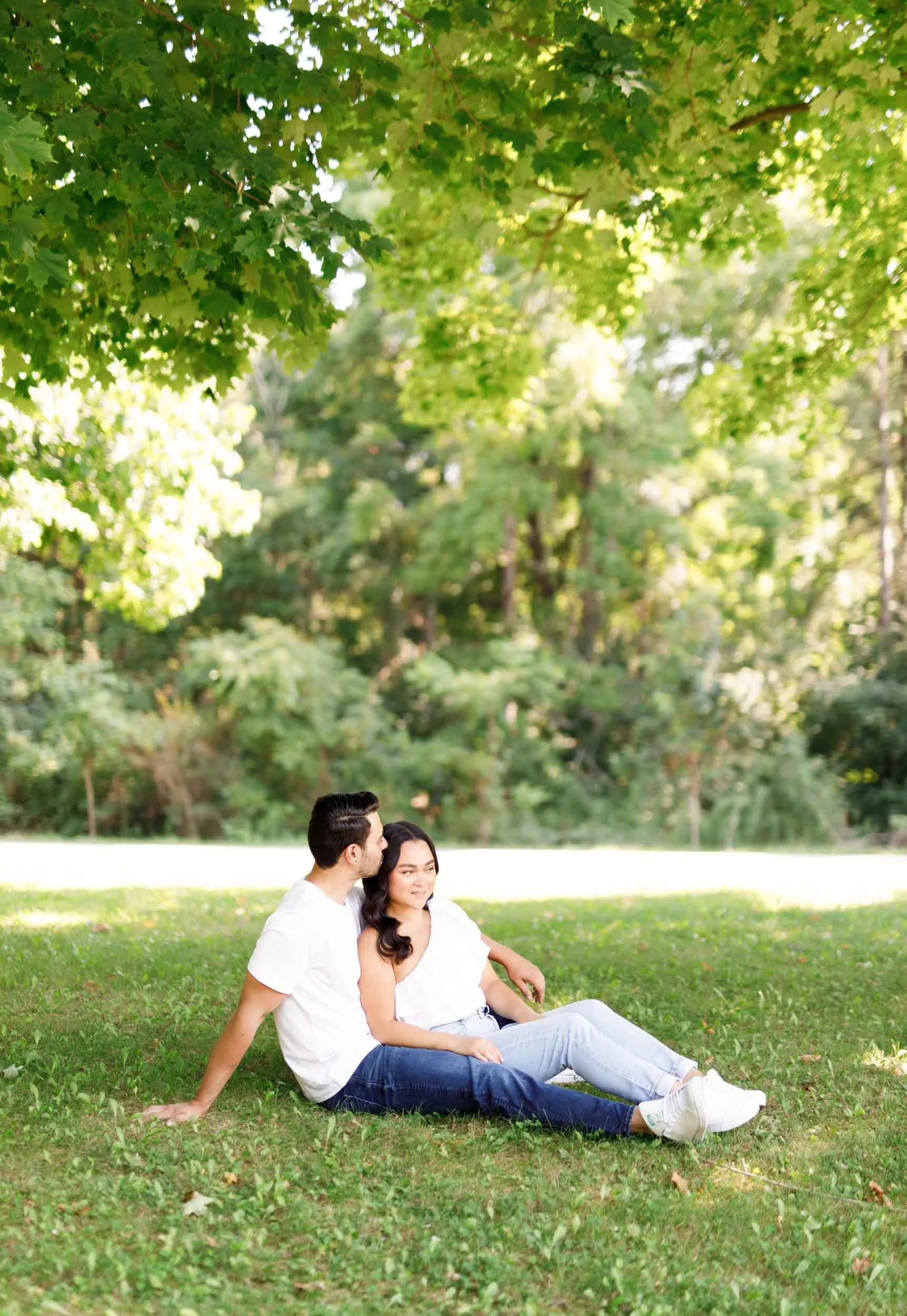 Engaged couple sitting together on the grass at Kortright Centre for Conservation in Woodbridge, Ontario
