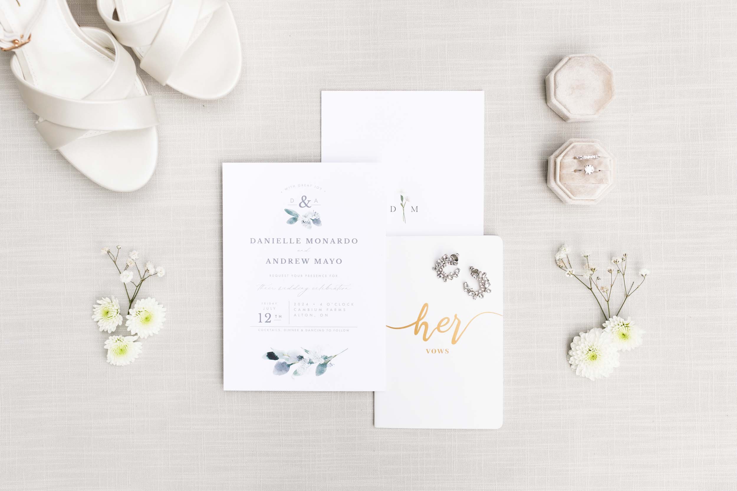 Flat lay of wedding invitation suite with bride’s shoes and floral details at a Cambium Farms wedding in Alton, Ontario