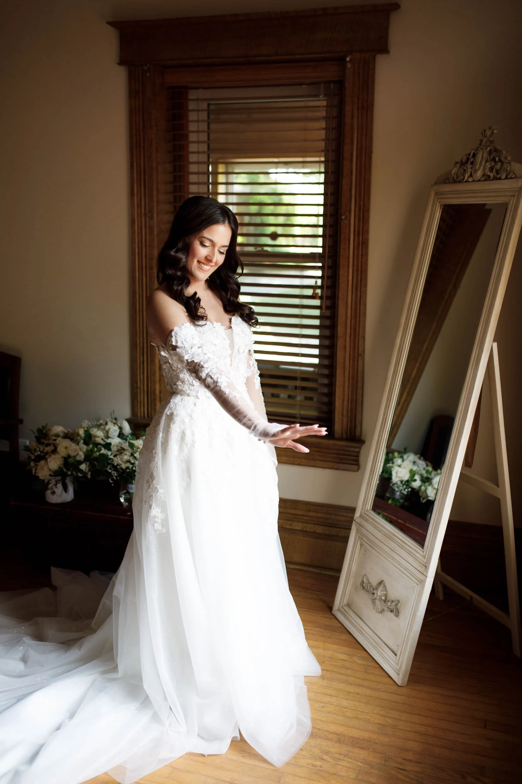 Bride standing in her wedding dress by a mirror at a Cambium Farms wedding in Alton, Ontario