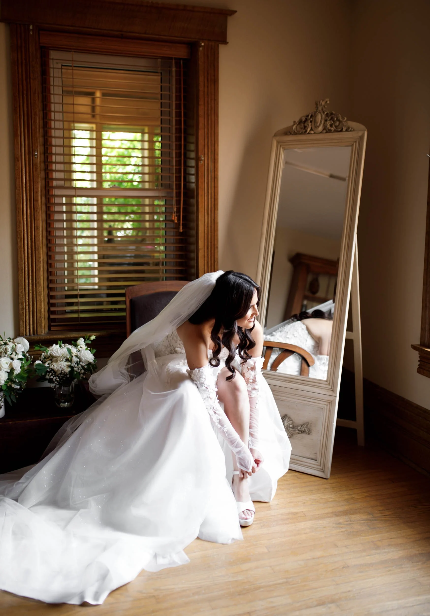 Bride sitting on the floor in her wedding dress adjusting her shoes at a Cambium Farms wedding in Alton, Ontario