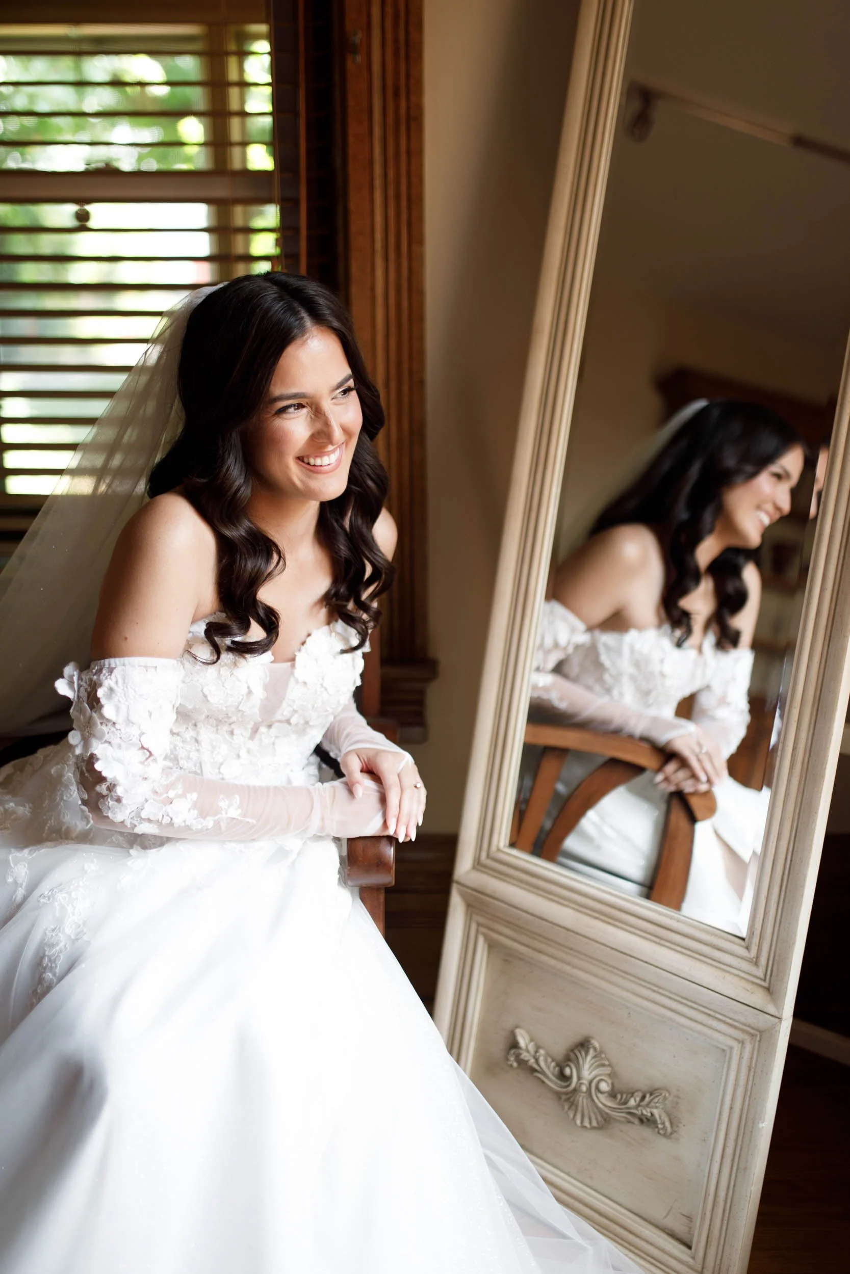 Bride smiling in her wedding dress in the mirror during bridal prep at Cambium Farms in Alton, Ontario