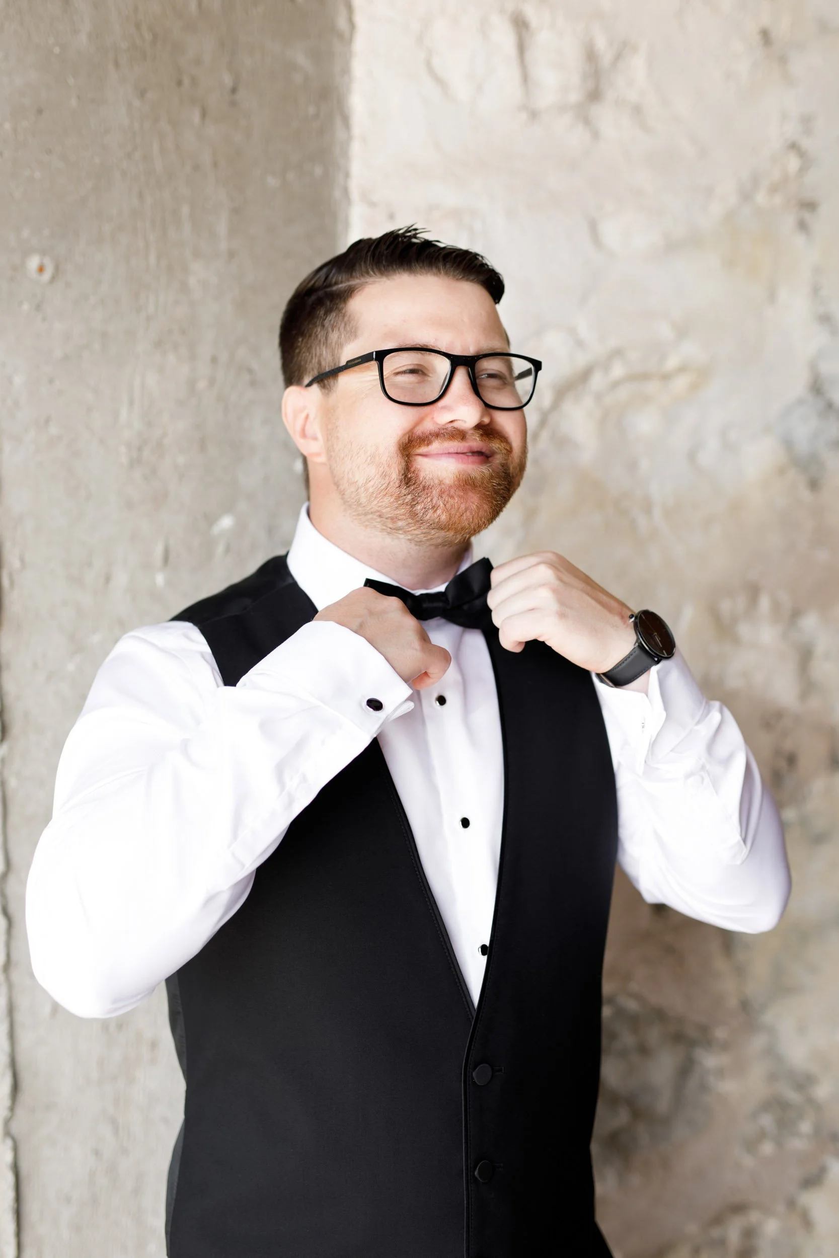 Groom adjusting his bow tie during groom prep at a Cambium Farms wedding in Alton, Ontario