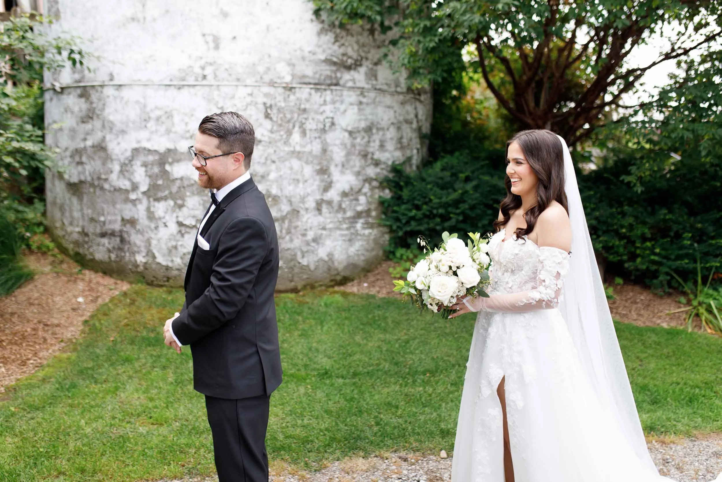 Bride and groom standing back to back before their first look at a Cambium Farms wedding in Alton, Ontario