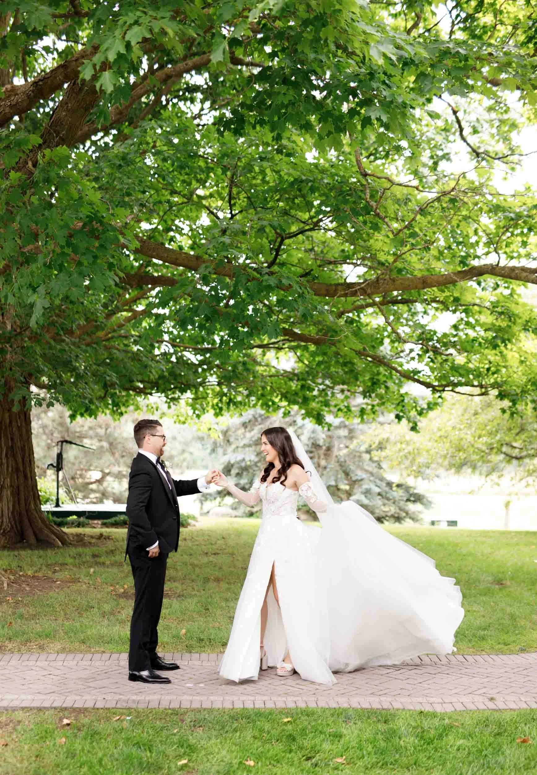 Bride and groom walking together beneath trees at a Cambium Farms wedding in Alton, Ontario