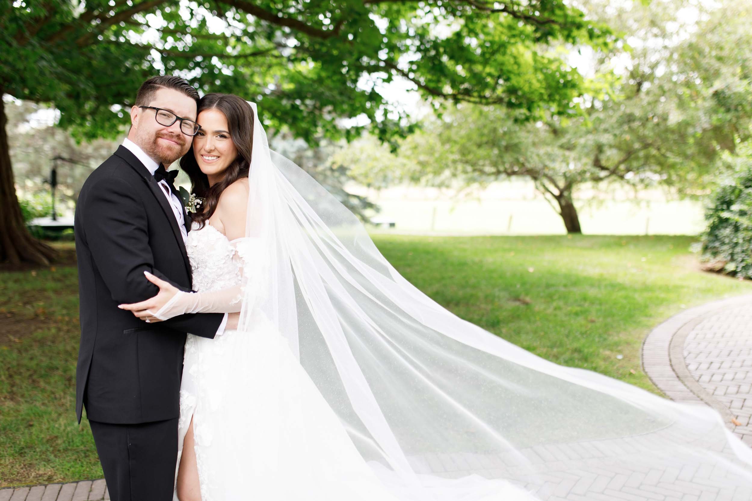 Bride and groom embracing with bride’s veil blowing at a Cambium Farms wedding in Alton, Ontario