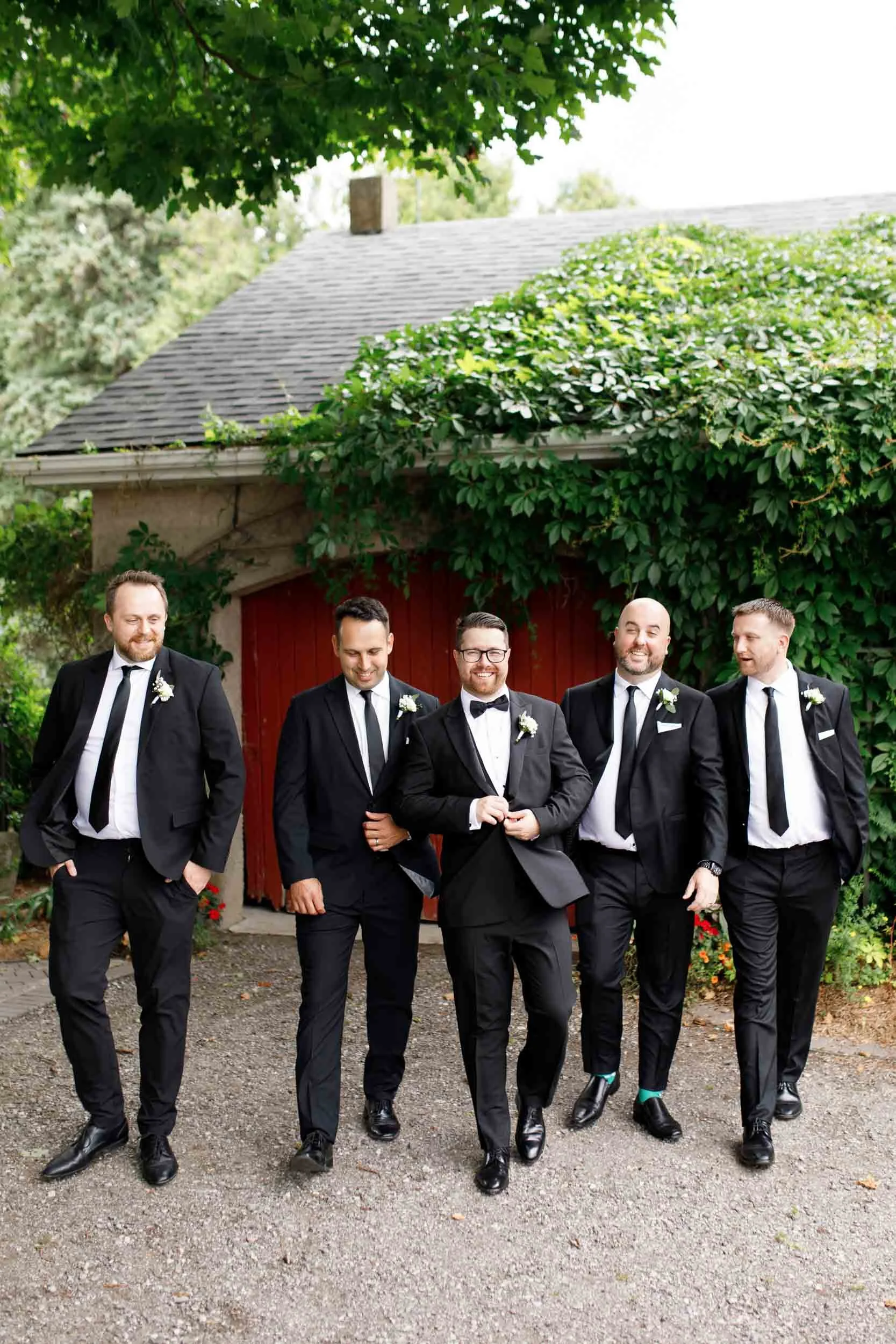 Groom walking with his groomsmen during portraits at a Cambium Farms wedding in Alton, Ontario